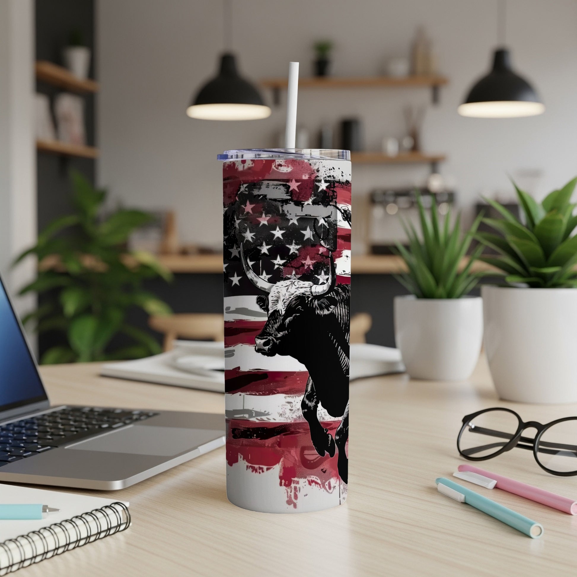 Bull on American flag tumbler with straw on a desk.