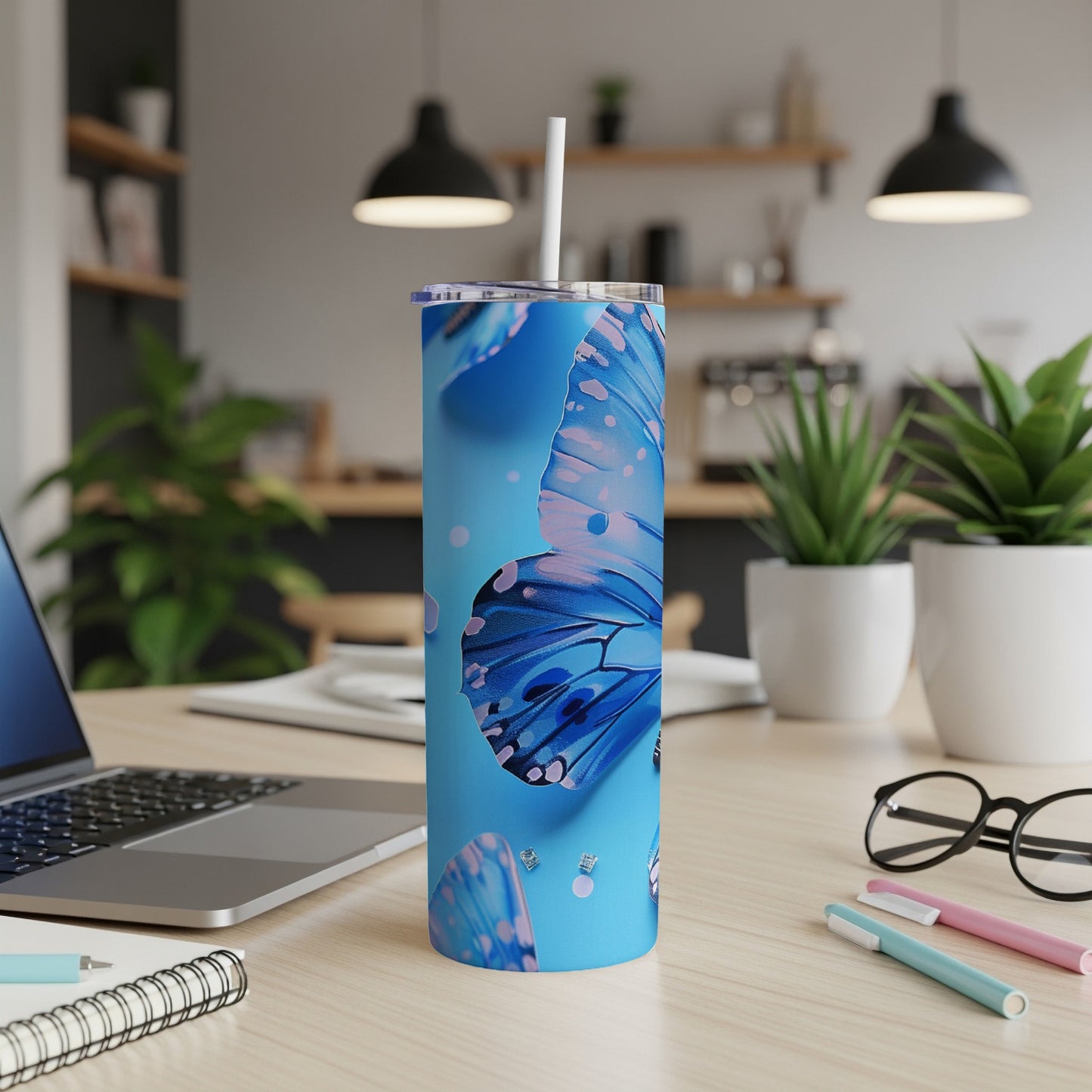 Blue butterfly tumbler with a white straw on a desk.