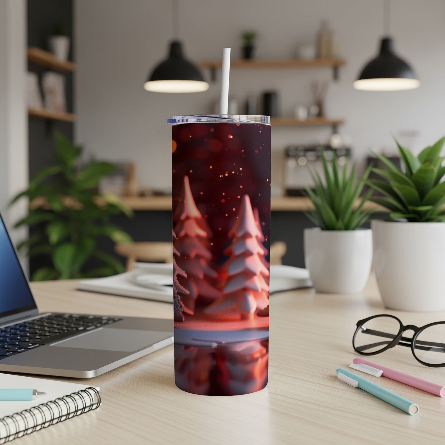 Red tumbler with festive winter trees and snow, standing on a desk.