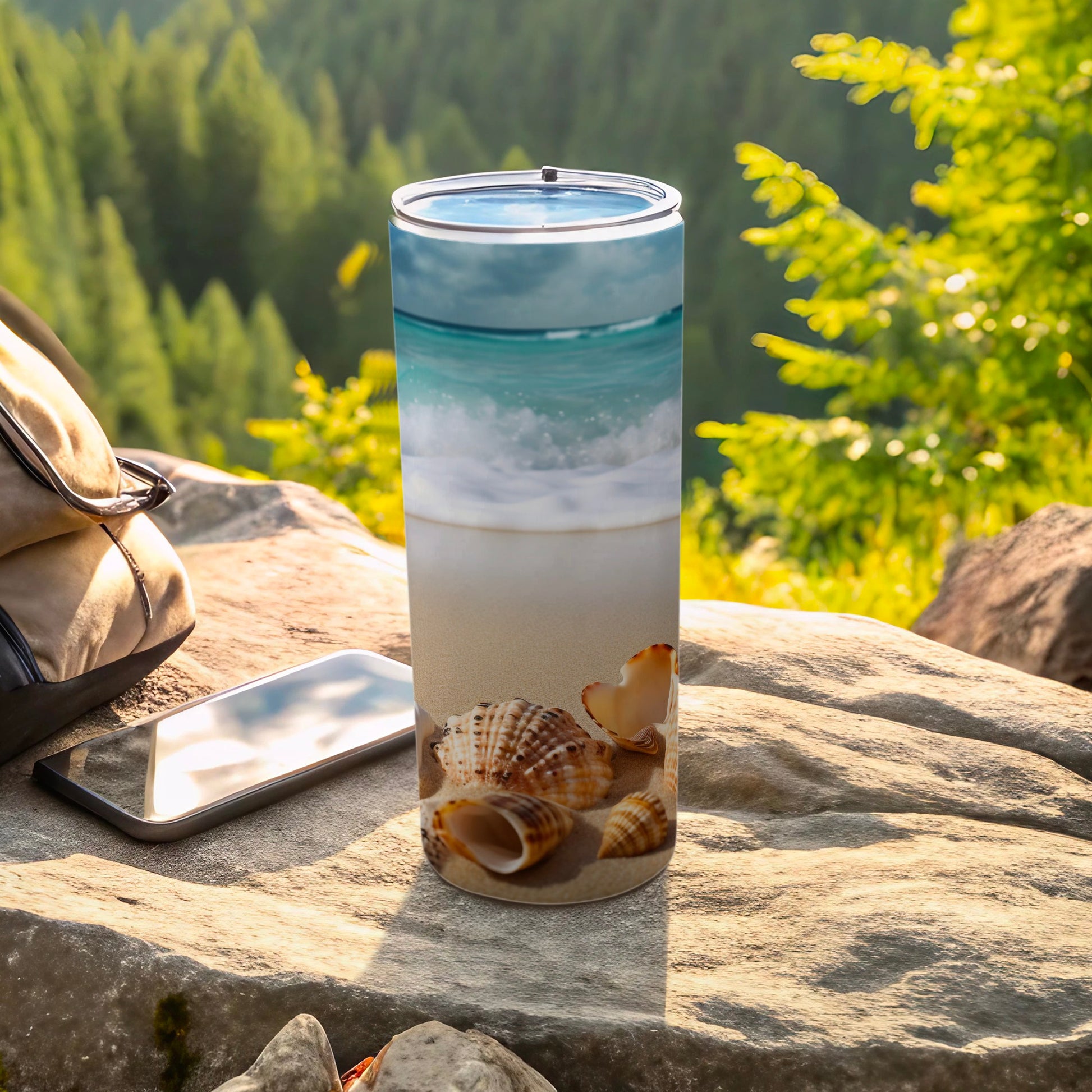 Tall insulated tumbler with beach and seashell design, outdoors.