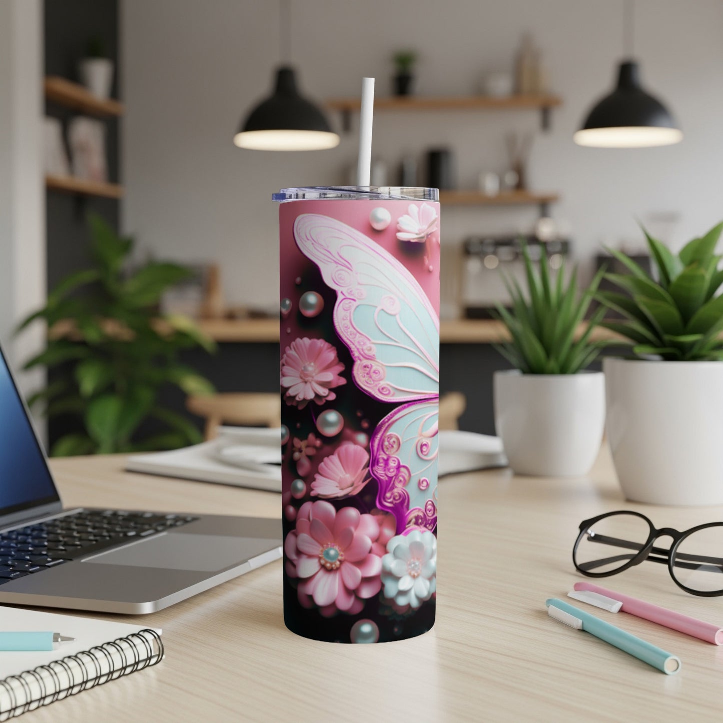Pink tumbler with butterfly and floral designs, straw inserted.