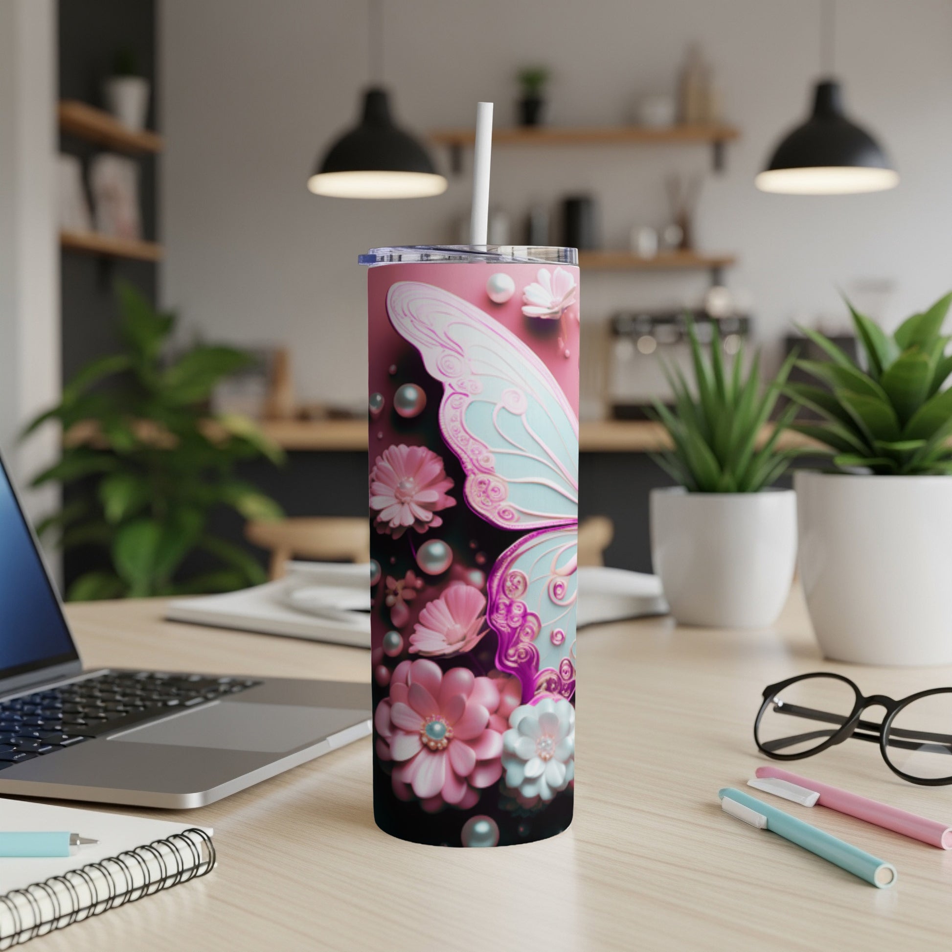 Pink tumbler with butterfly and floral designs, straw inserted.
