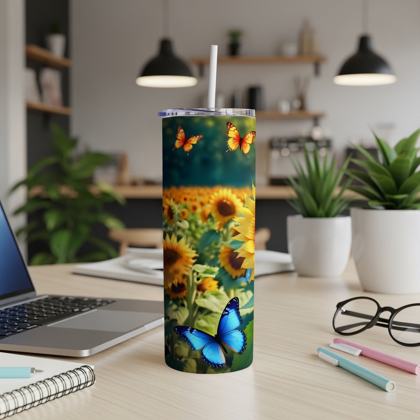 Sunflower and butterfly tumbler on a desk with a laptop and stationery.