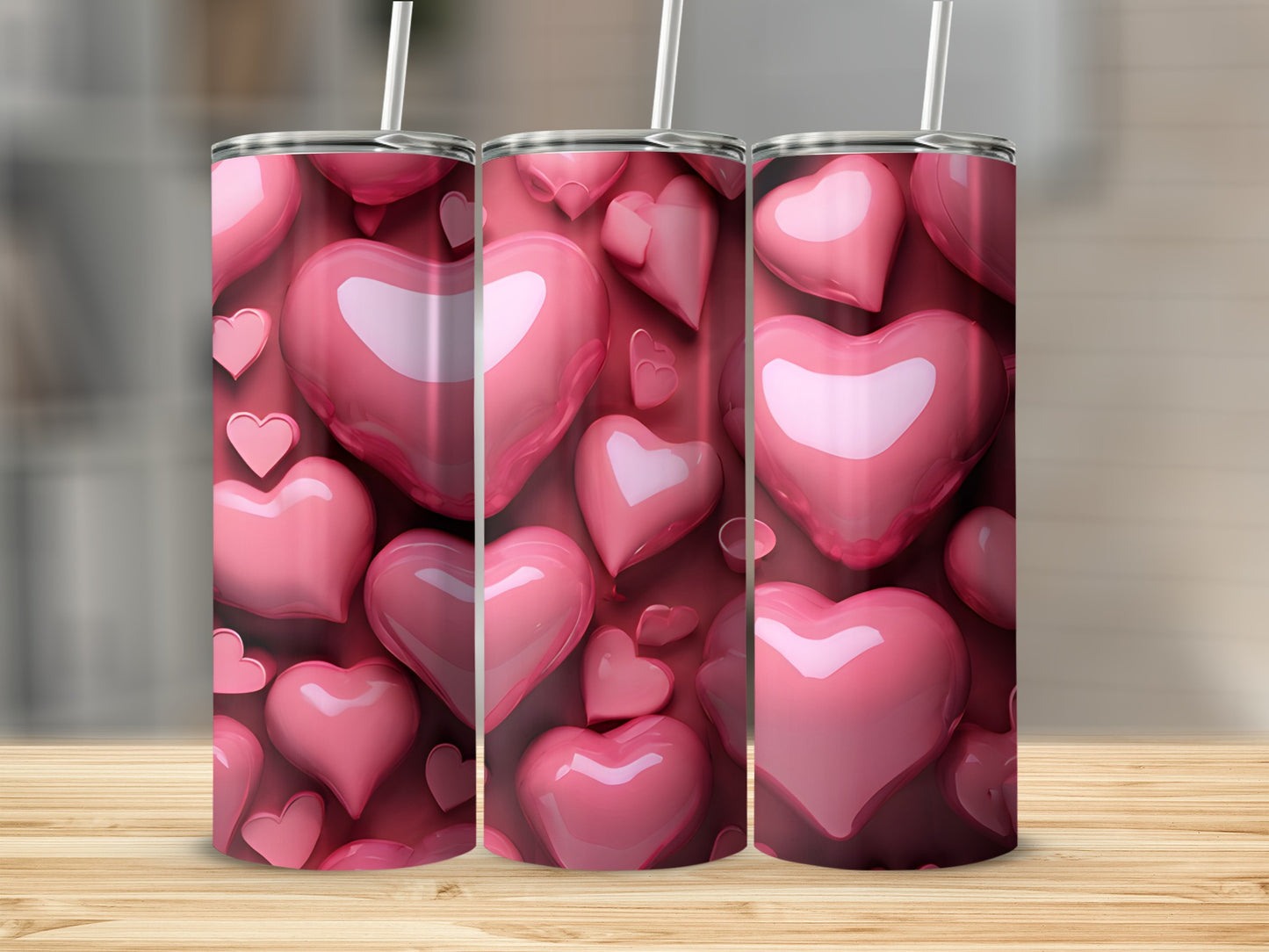 Pink hearts pattern on three tumblers with straws on a wooden surface.