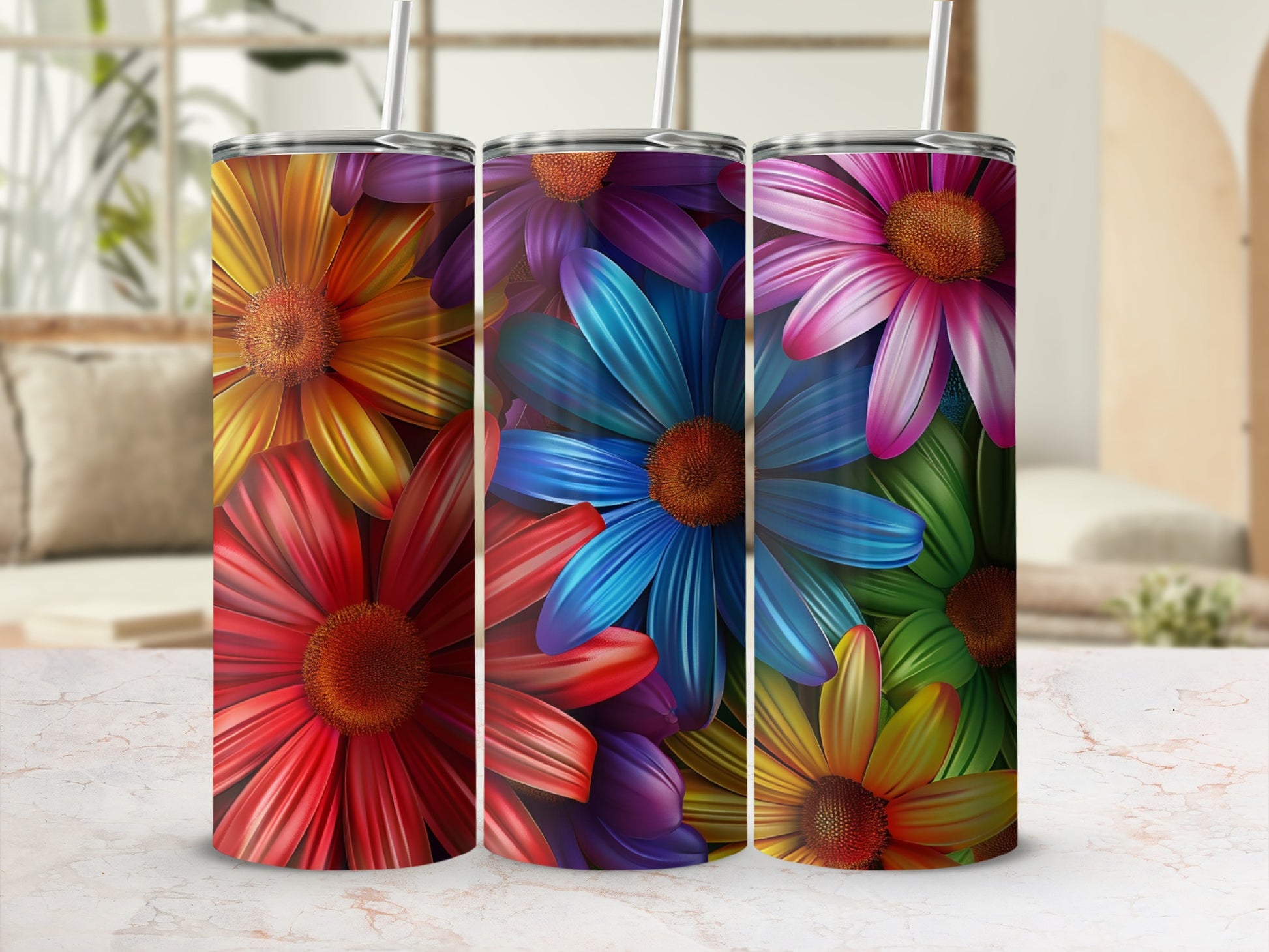 Three colorful floral tumblers with straws on a marble surface.