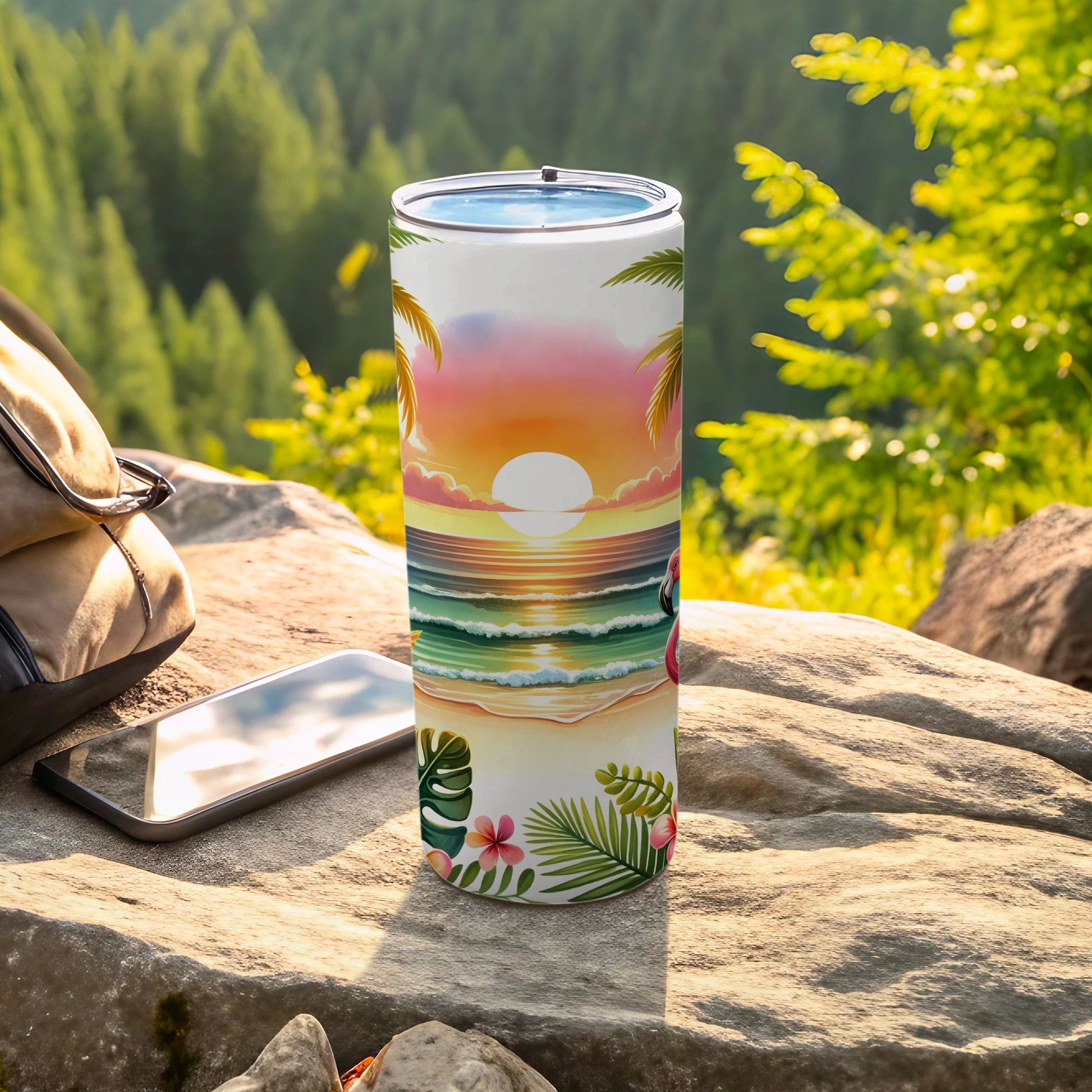 Tumbler with tropical sunset beach scene and flamingo, next to phone and backpack.
