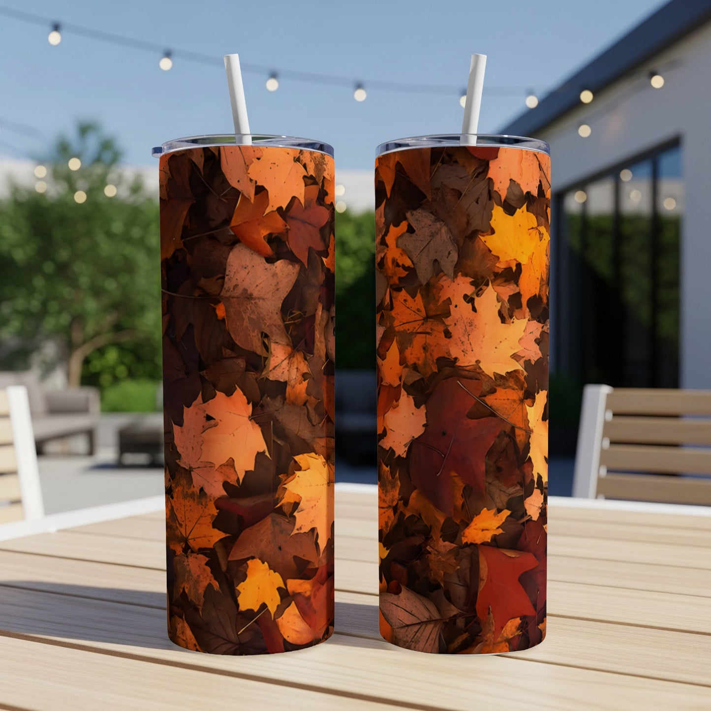 Two tumblers with an autumn leaf pattern on an outdoor table.