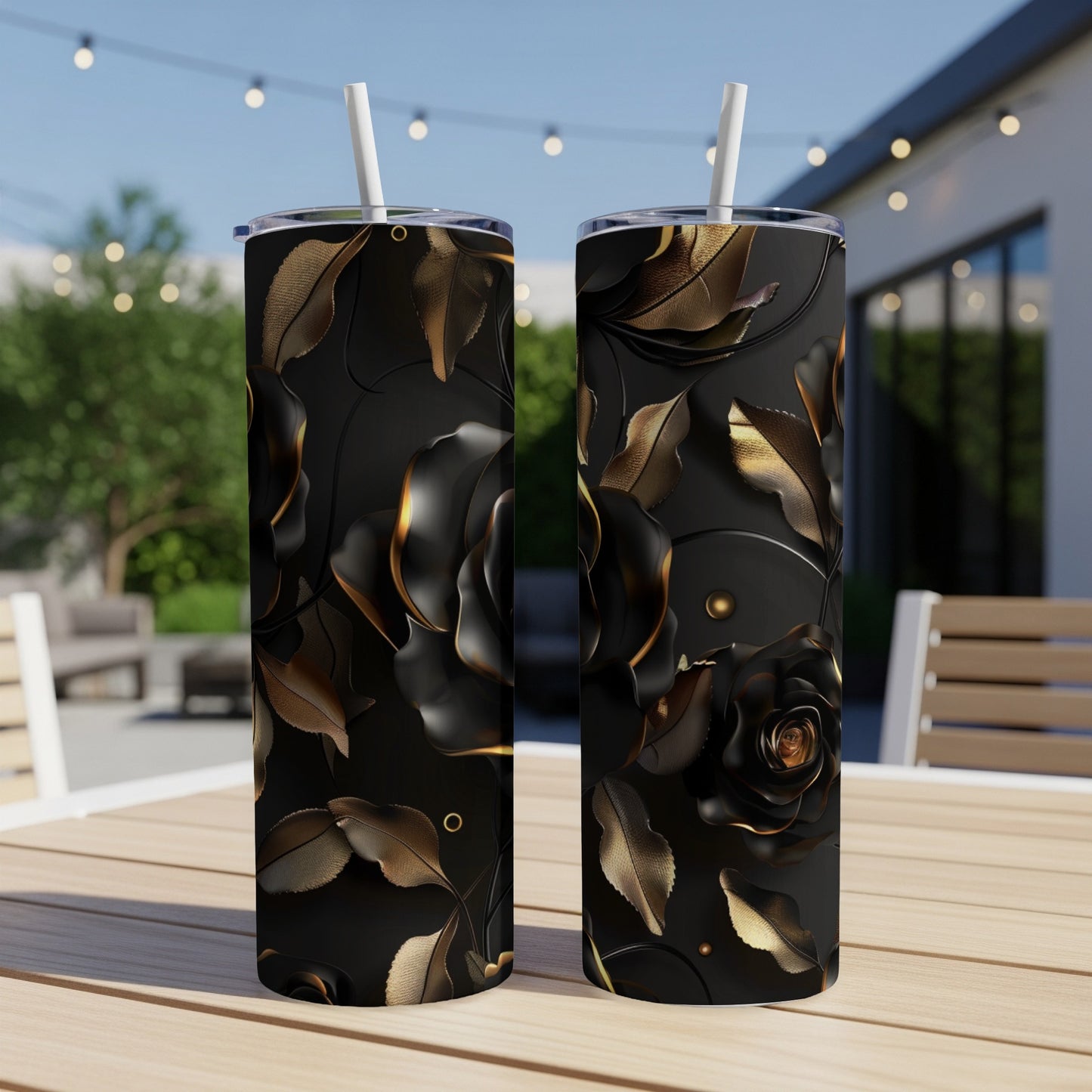 Two black tumblers with gold rose and leaf designs sit on a table.
