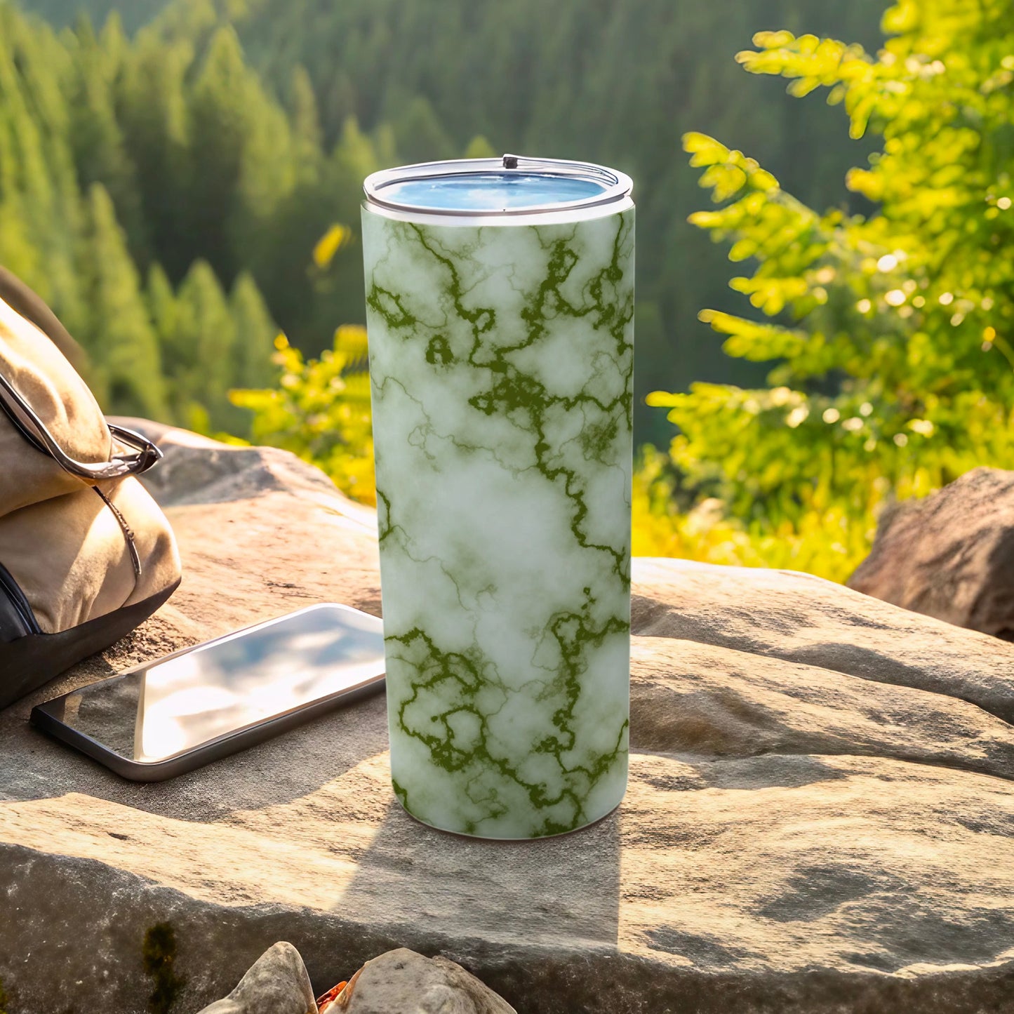 Green marble pattern tumbler with a backpack and phone on a rock.