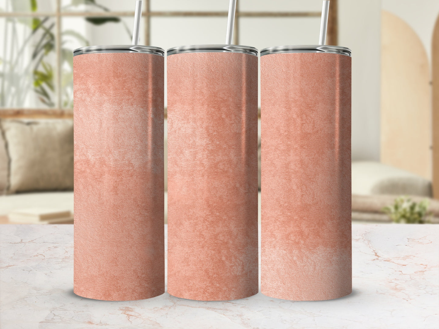Three coral gradient tumblers with silver lids and straws on a marble surface.