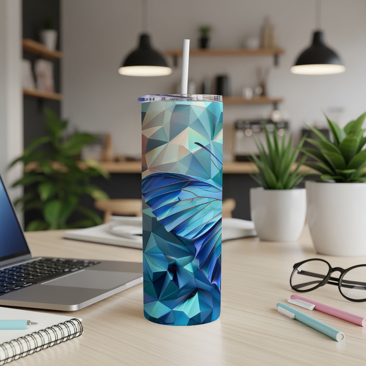 Blue butterfly tumbler with geometric pattern and straw on desk.