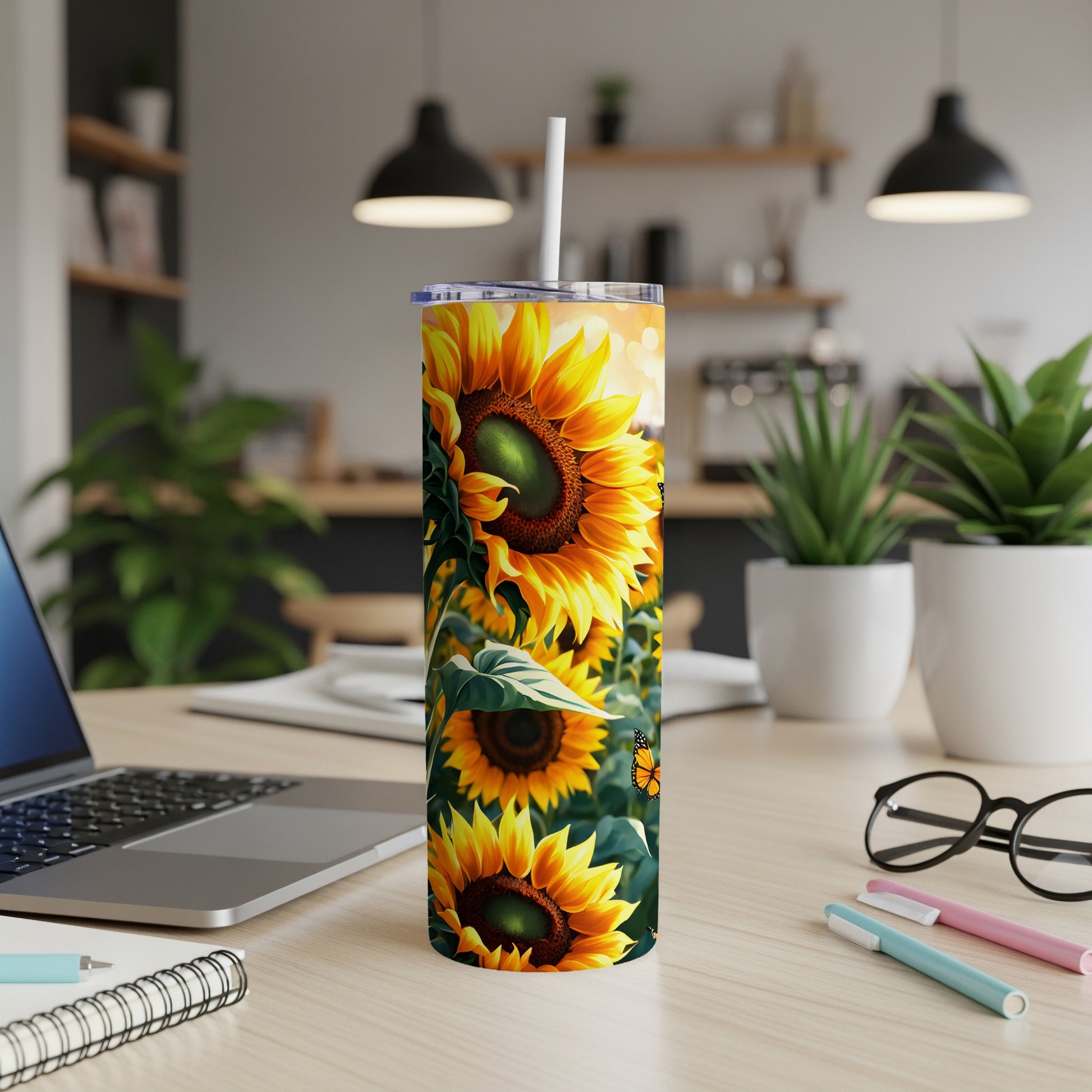 Sunflower tumbler with straw on a desk with a laptop.