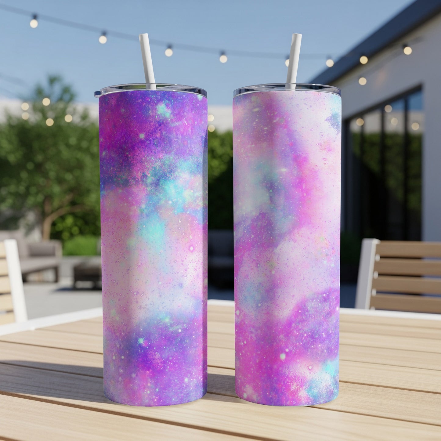 Two tall tumblers with a pink, purple, and teal galaxy pattern and white straws.