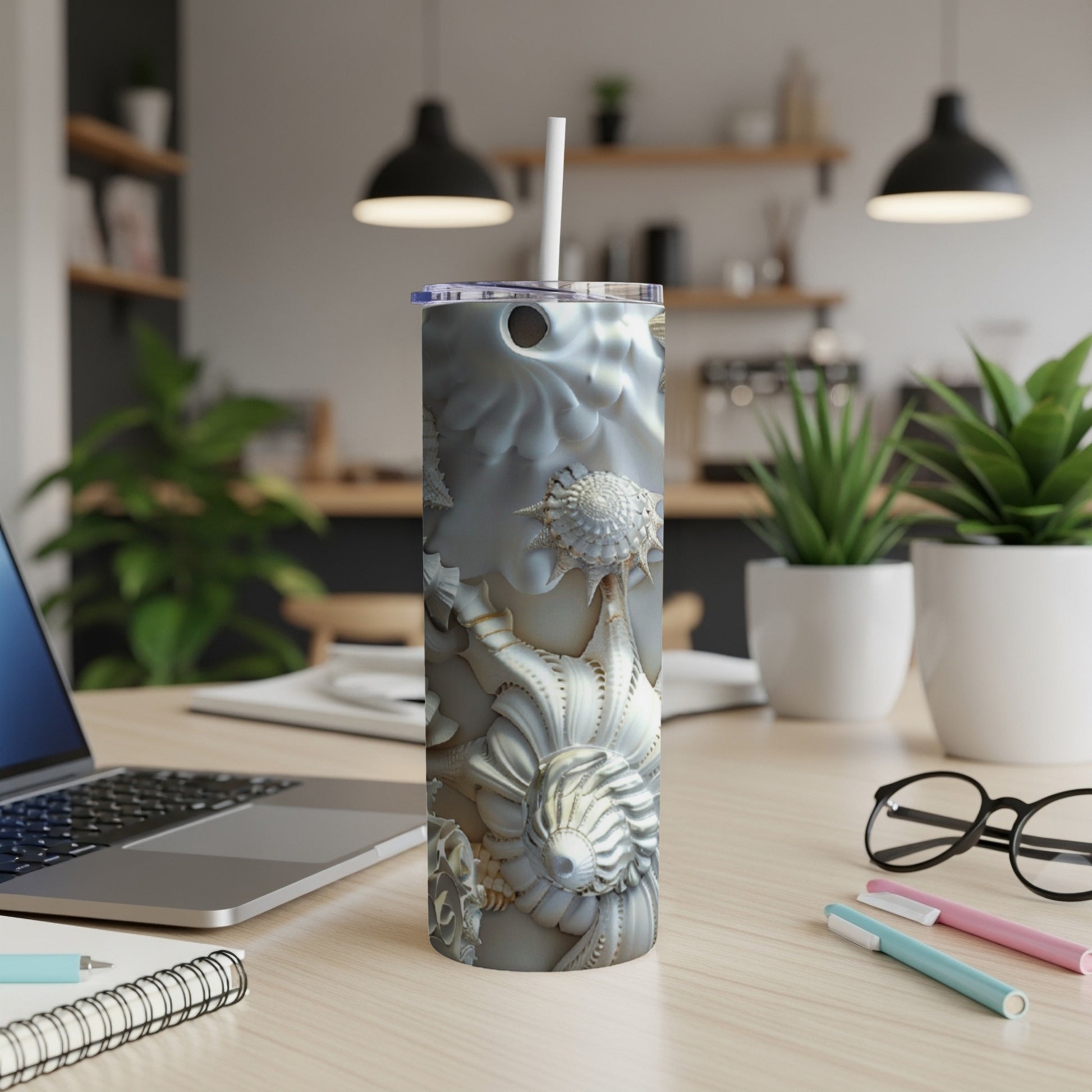 Seashell pattern tumbler with straw on a wooden desk.