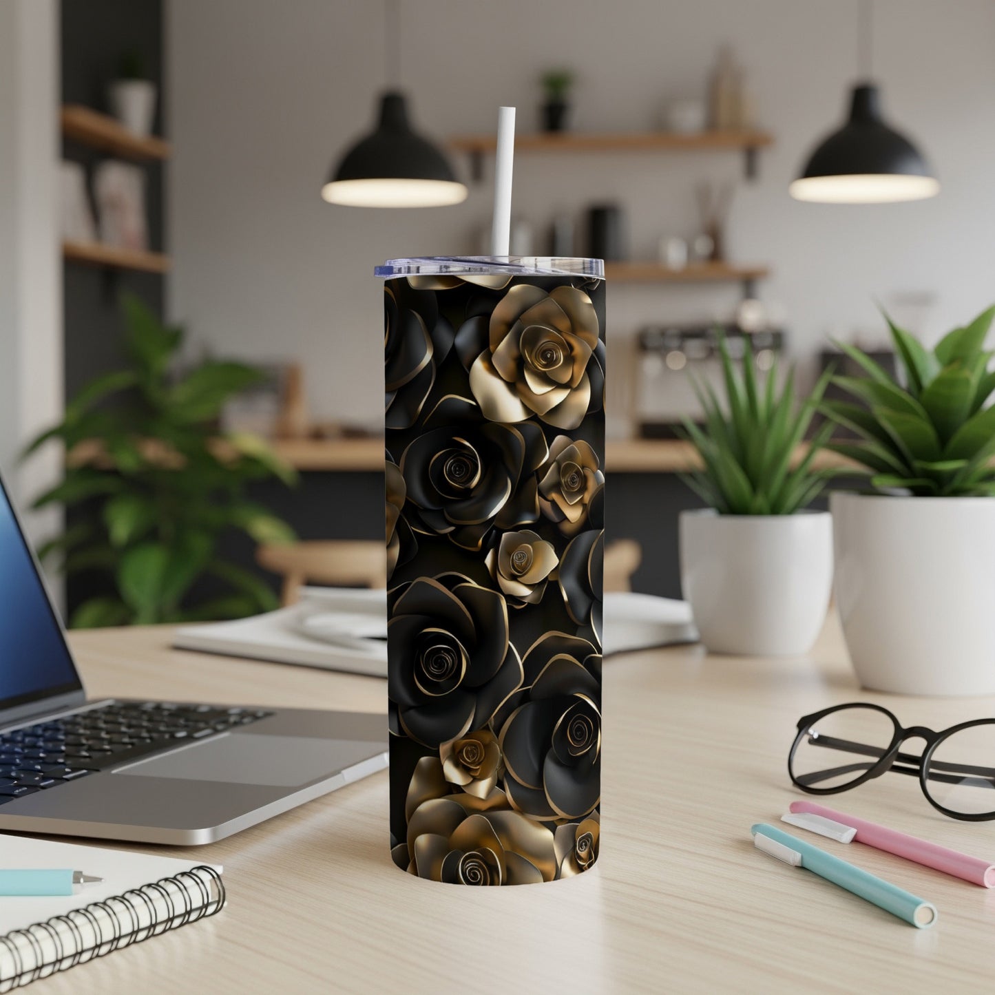 Black and gold floral pattern tumbler with a straw on a desk.