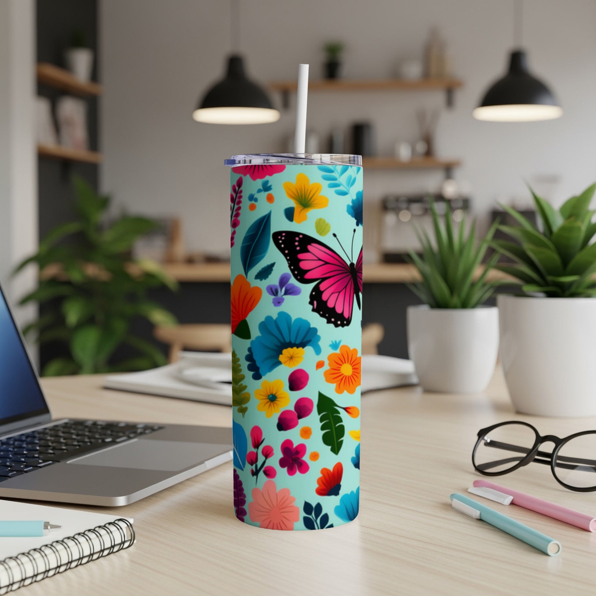 Turquoise tumbler with colorful floral and butterfly pattern, straw inserted.