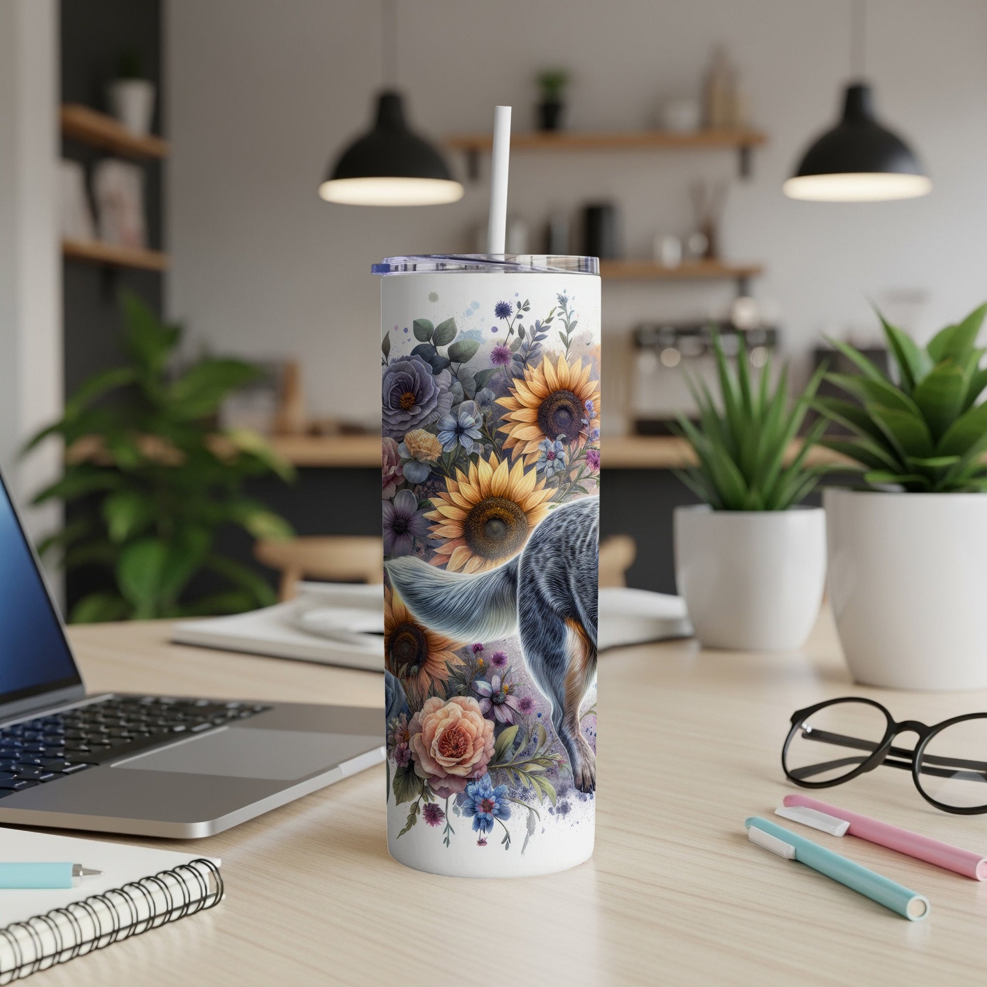 Tumbler with floral pattern and dog's tail, on a desk.