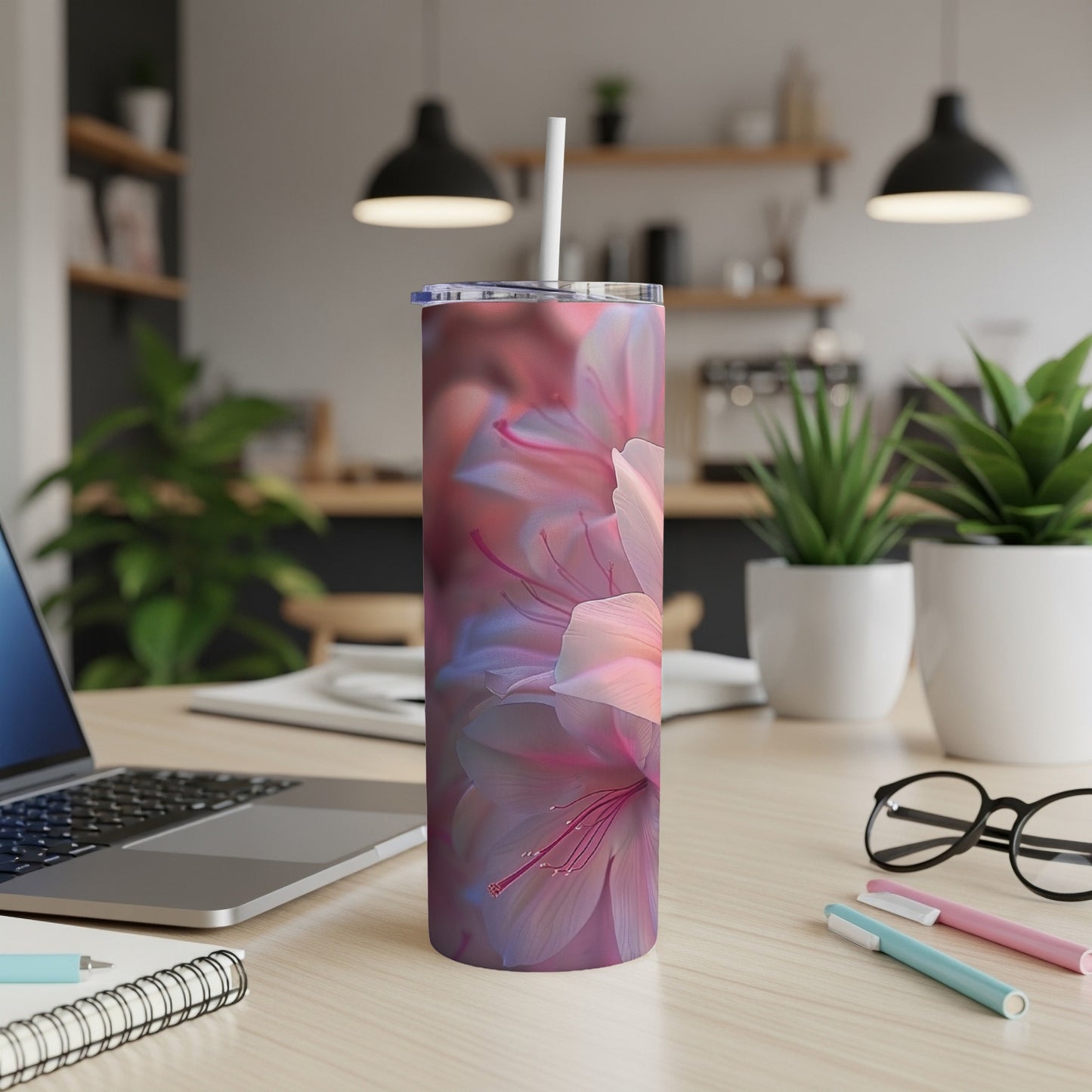 Tumbler with pink and blue floral design, straw, and laptop.