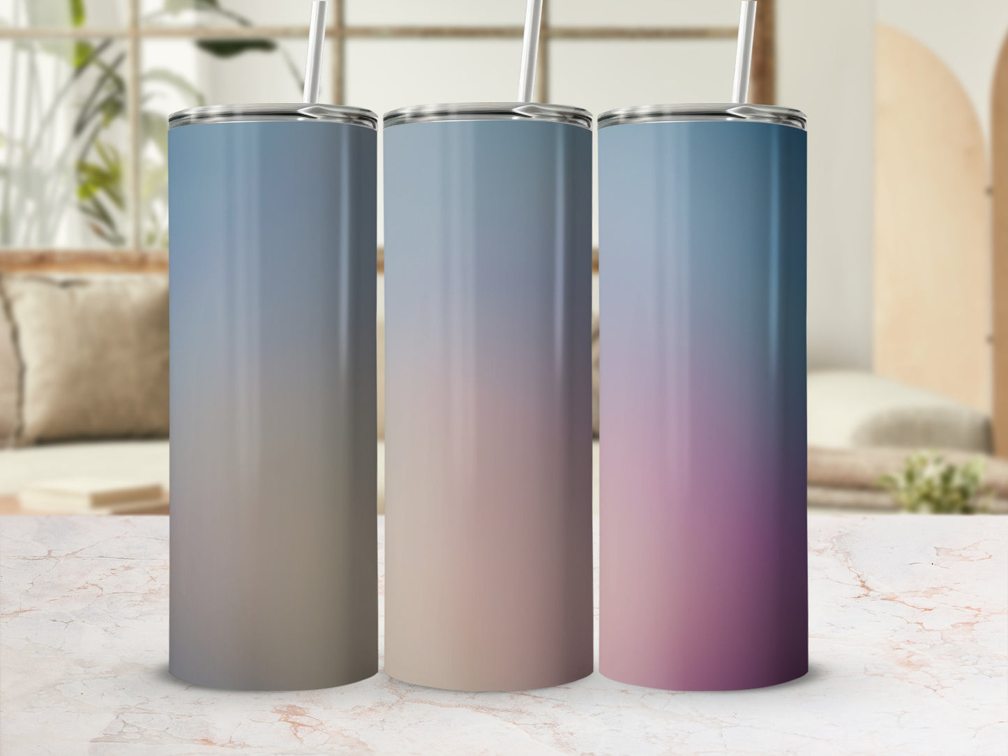 Three gradient tumblers with straws on a marble surface.