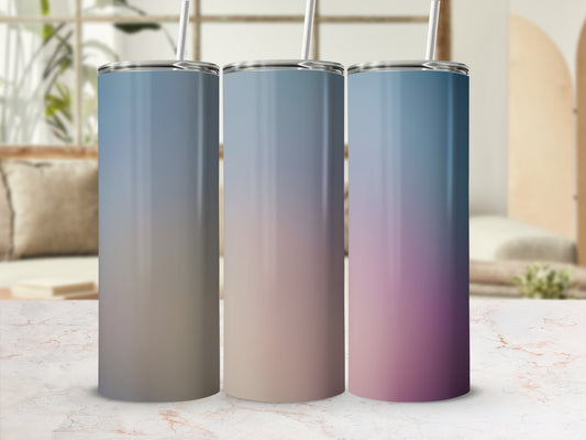 Three gradient tumblers with straws on a marble surface.