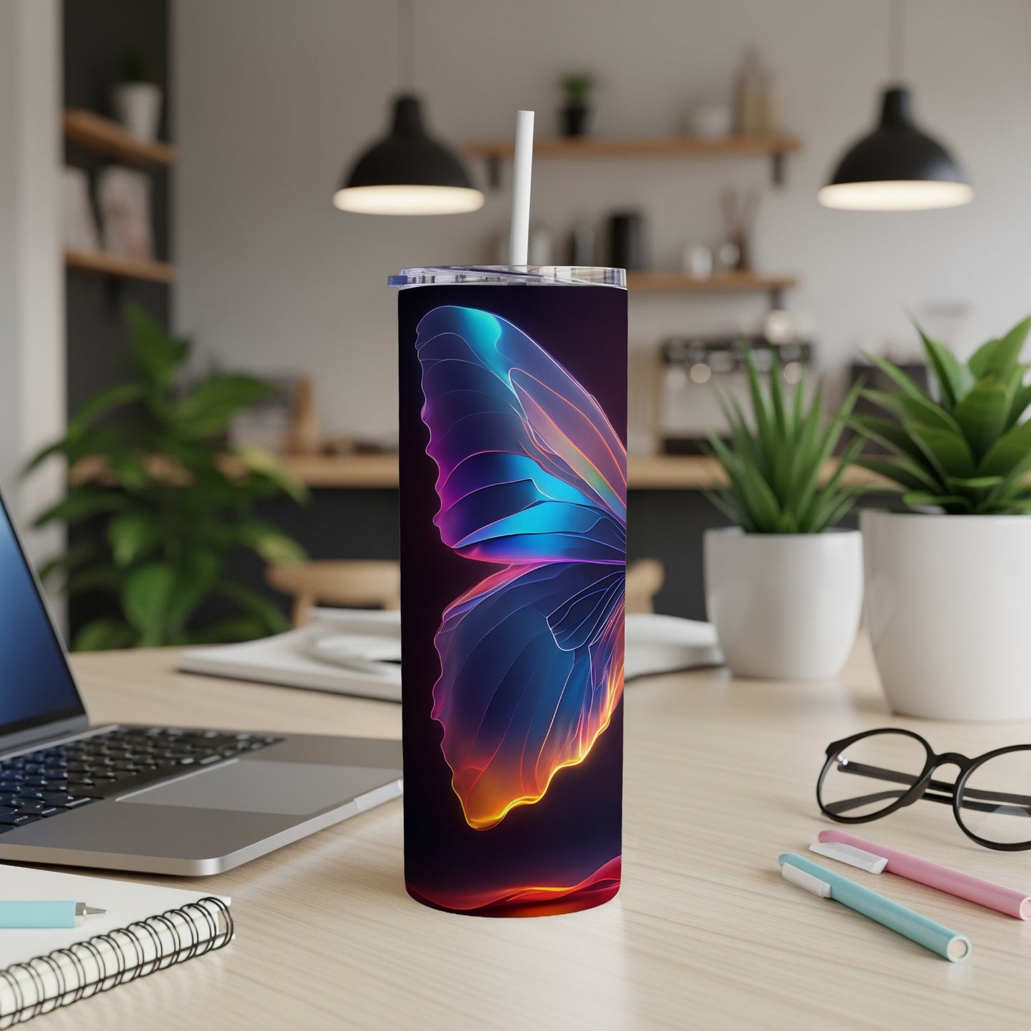Glow butterfly tumbler with straw on desk with laptop and pens.