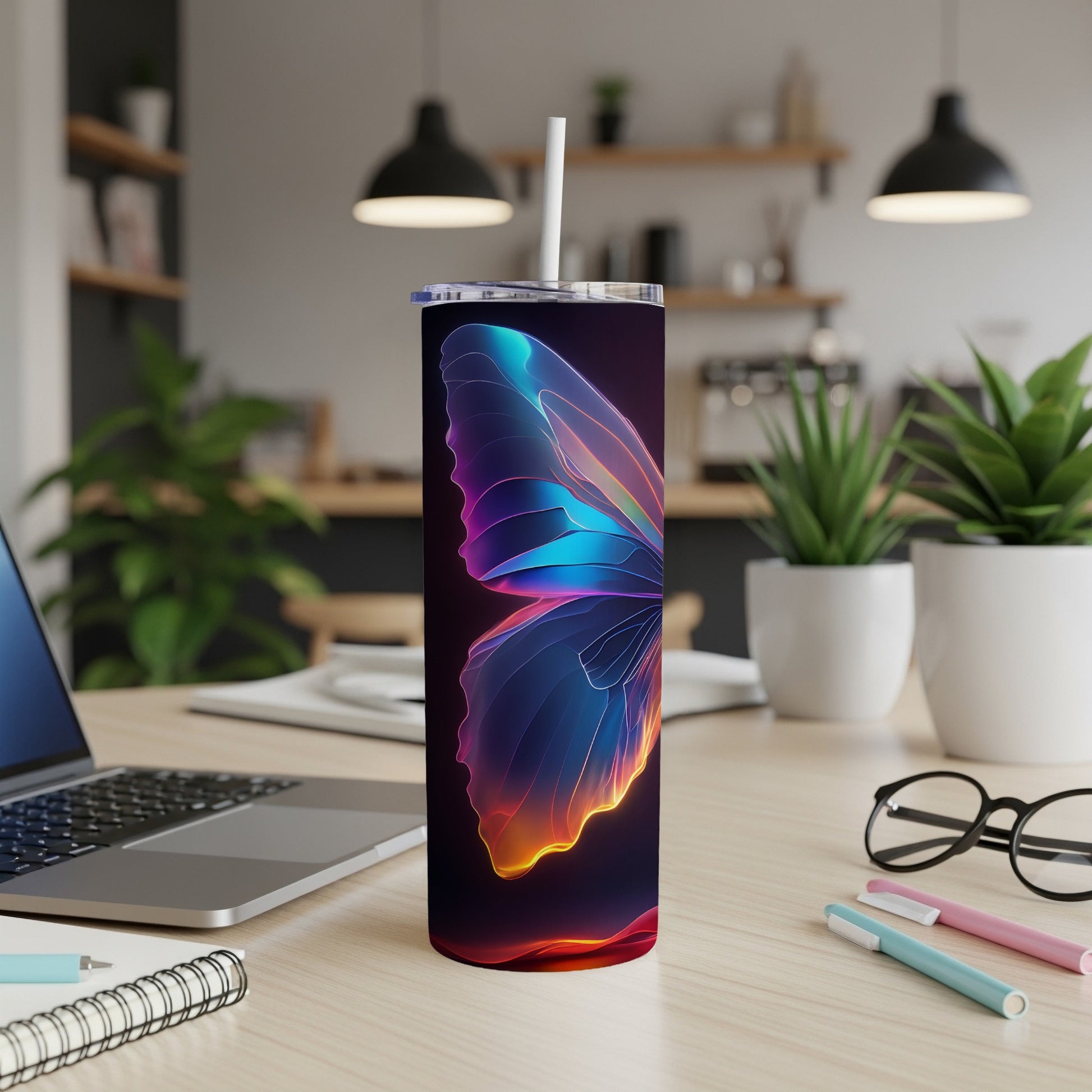 Glow butterfly tumbler with straw on desk with laptop and pens.