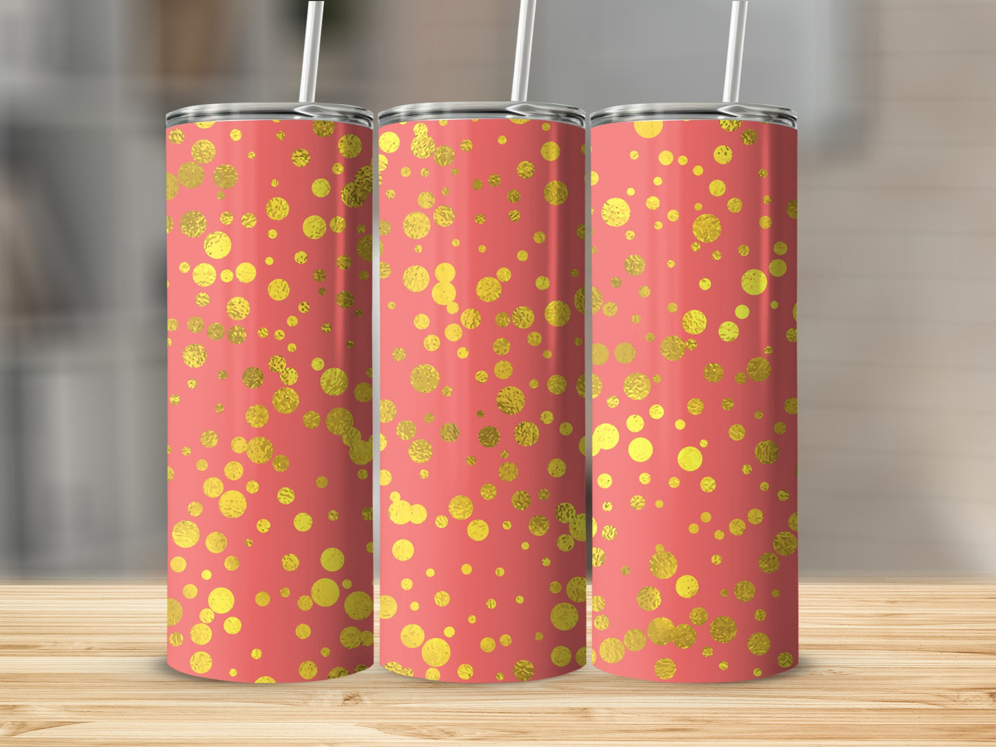 Three coral tumblers with gold textured polka dot pattern, standing on wood table.