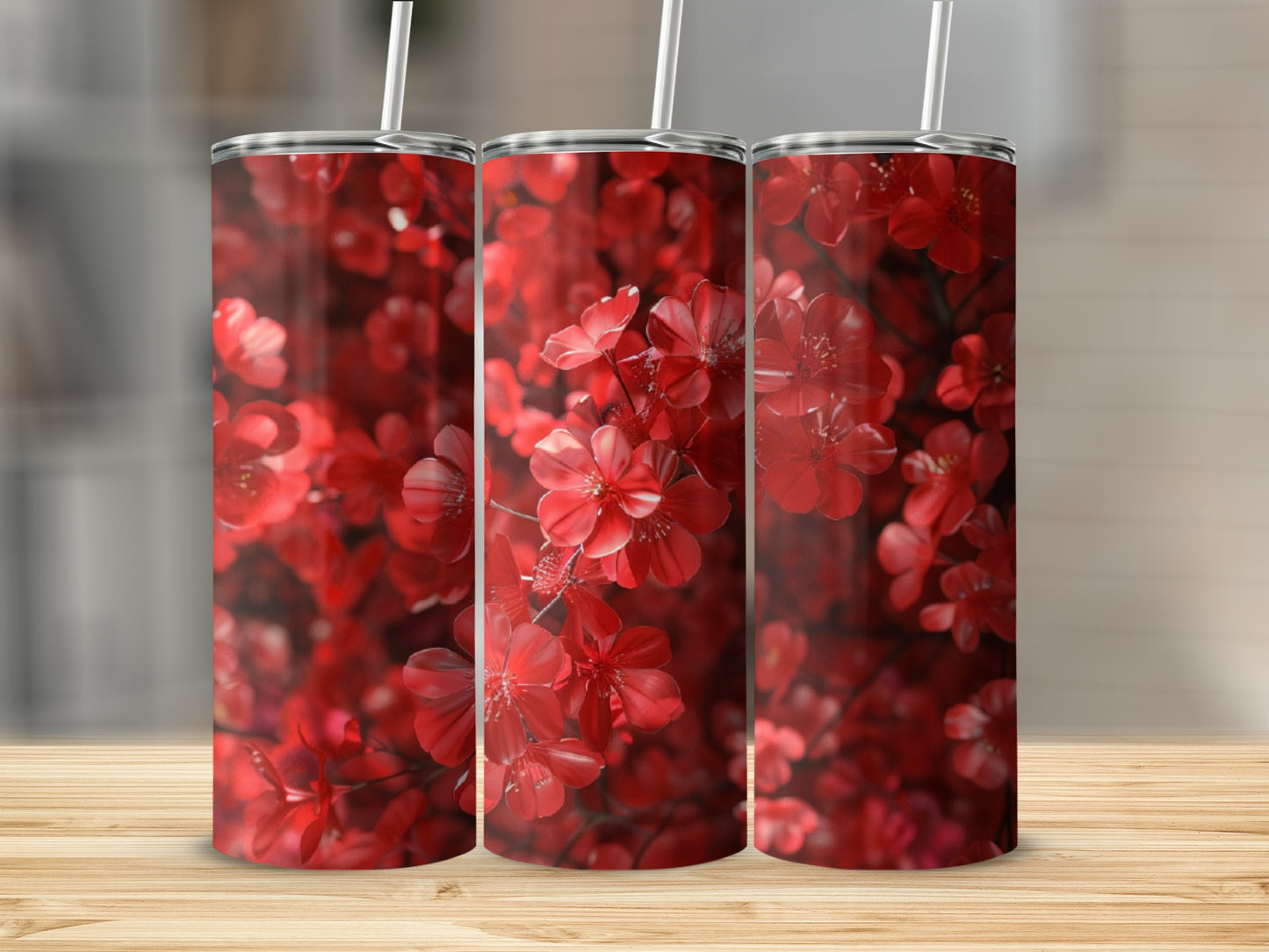Three tumblers with a vibrant red floral pattern sit on a wooden surface.