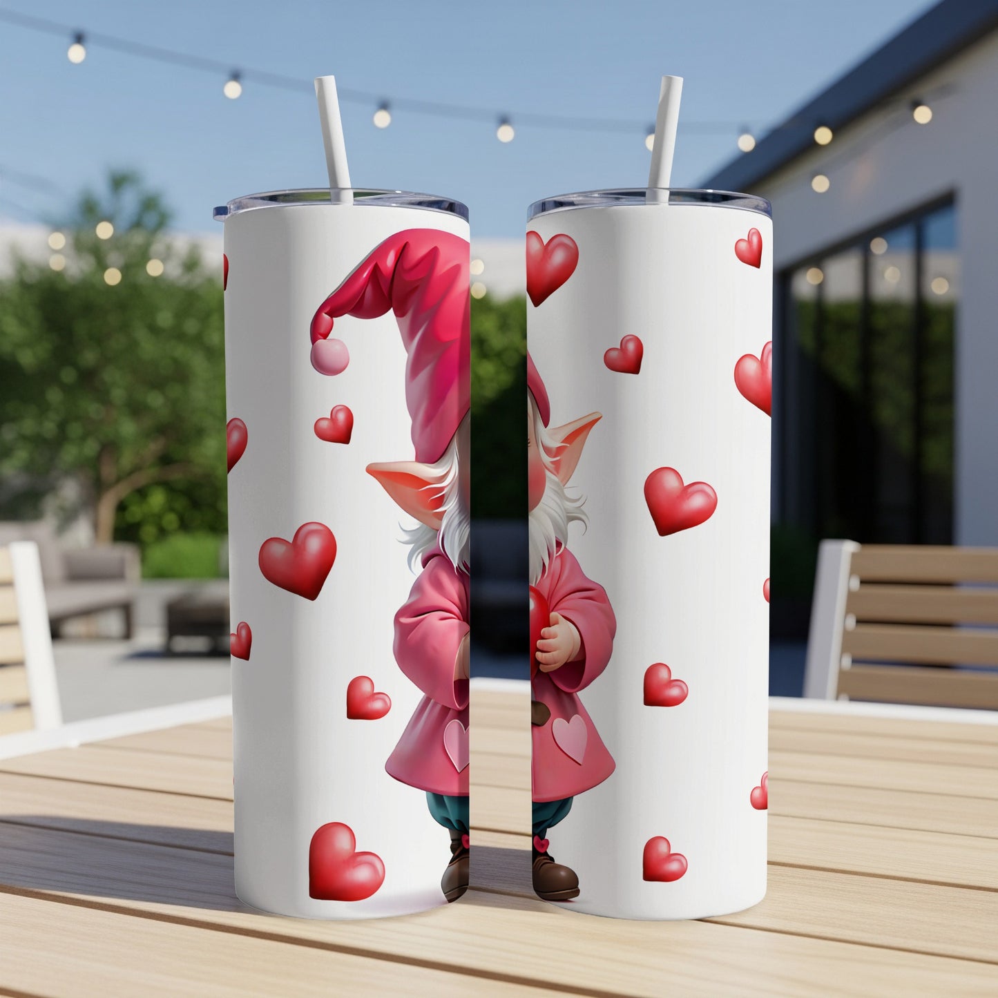 Two tumblers with a gnome and hearts design on an outdoor table.
