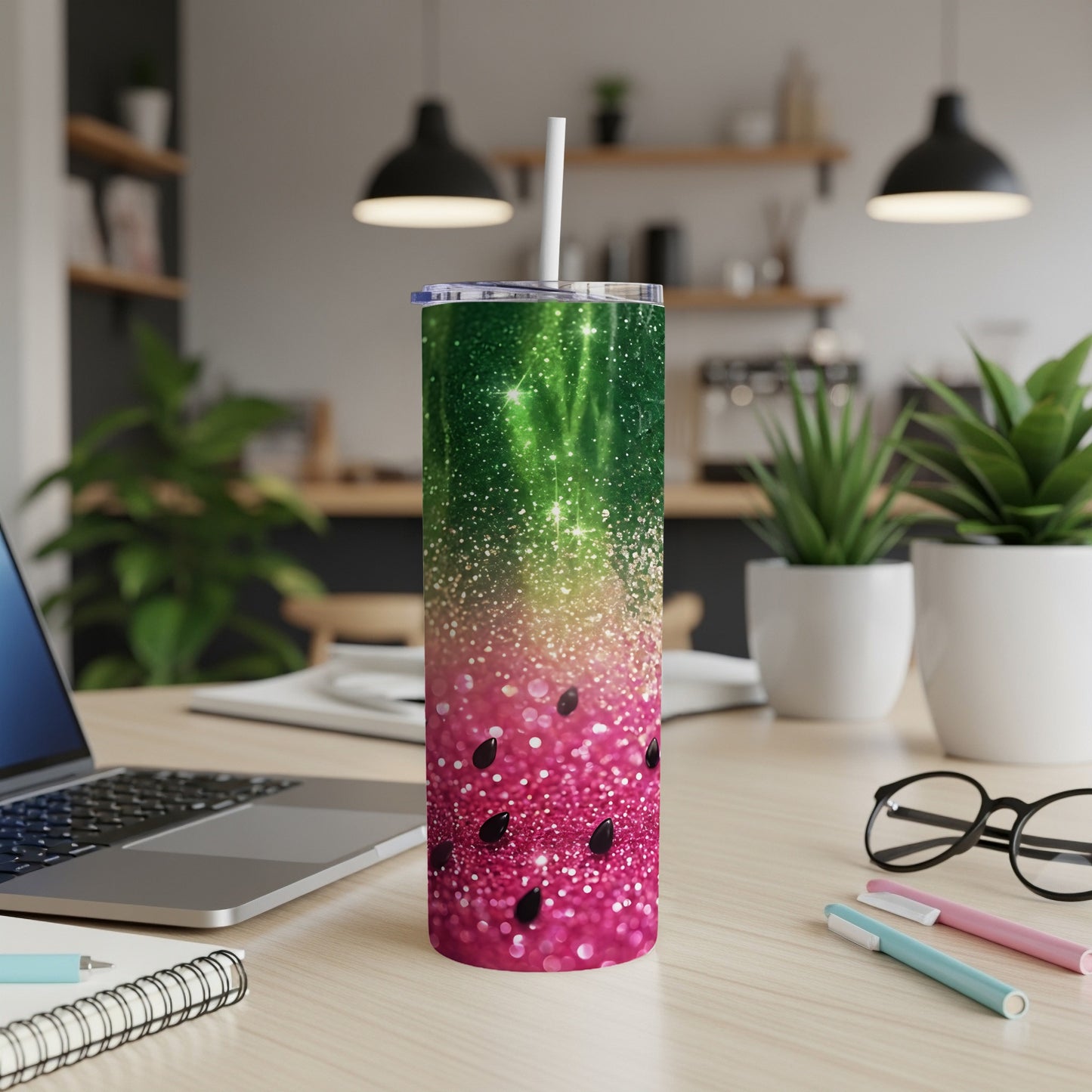 Glittering watermelon tumbler with a straw, on a desk with a laptop.