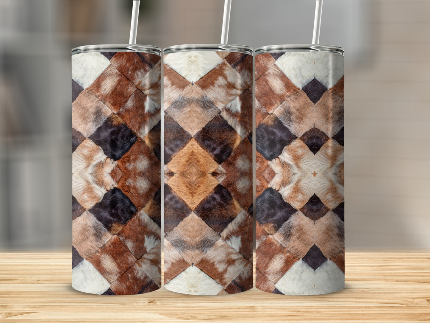 Three tumblers with a diamond-shaped cowhide pattern, on a wooden surface.