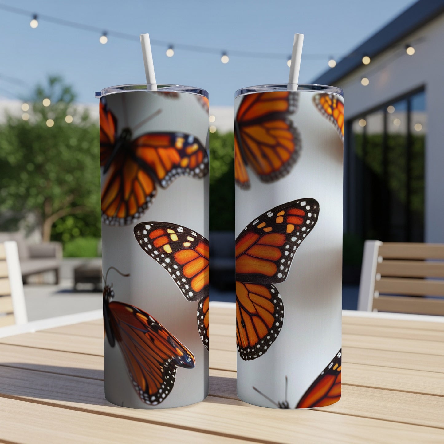 Two skinny tumblers with monarch butterfly wings design on a table.