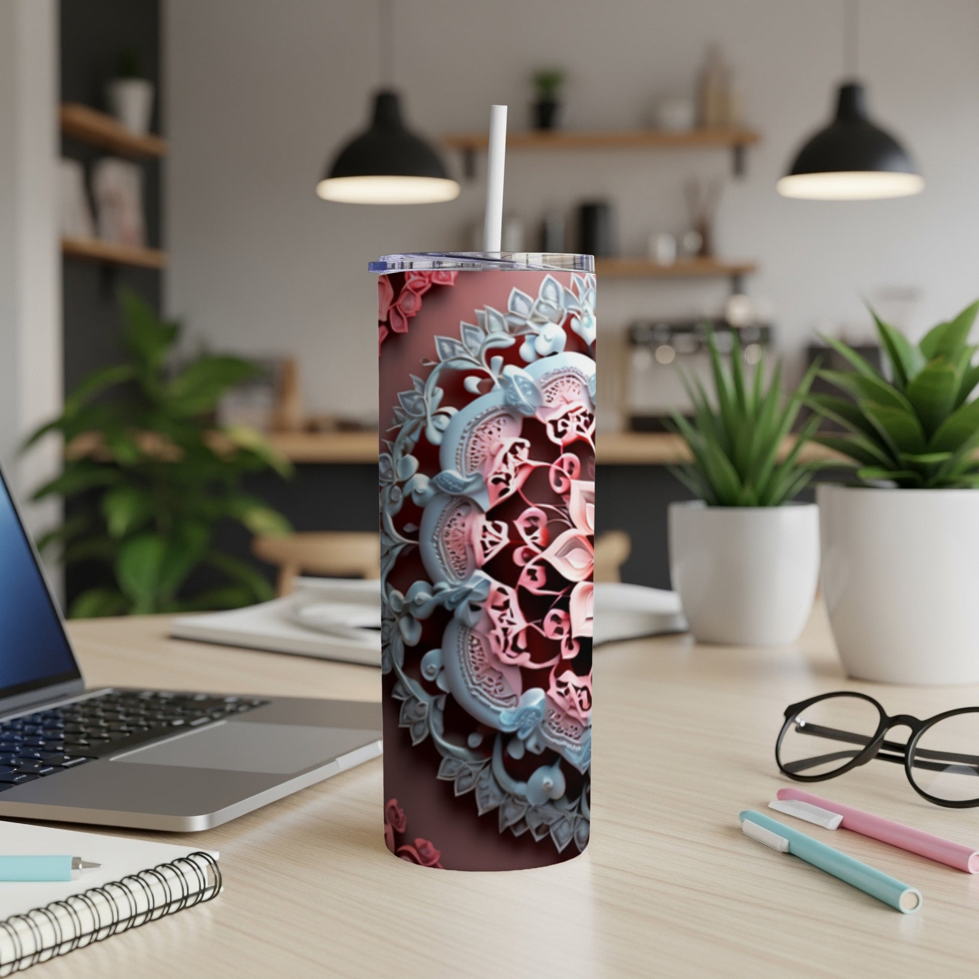Tumbler with intricate floral mandala design, straw in lid, on desk.