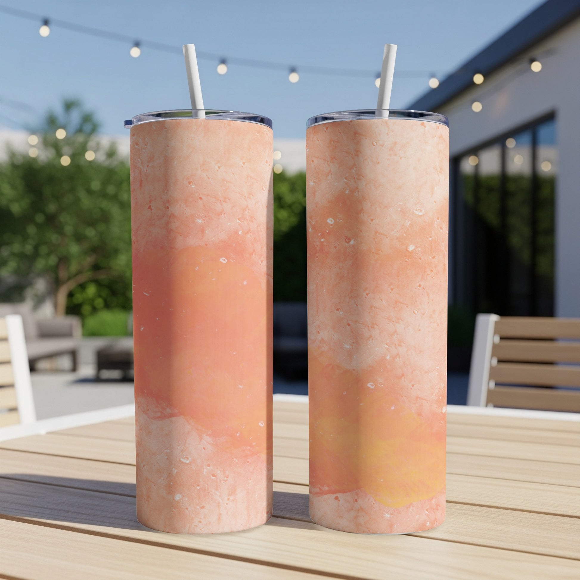 Two tall tumblers with a marbled peach and orange design and white straws.