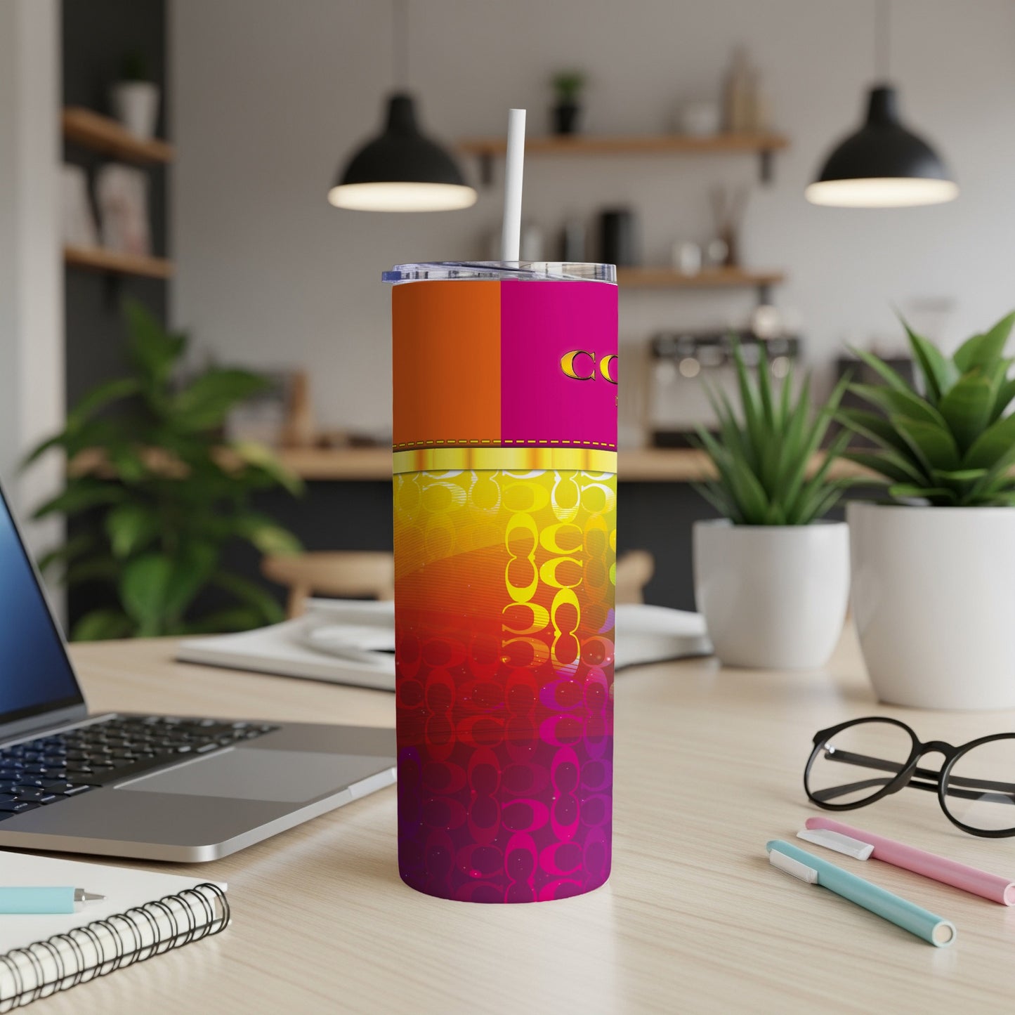 Colorful tumbler with Coach pattern, straw, and desk accessories.