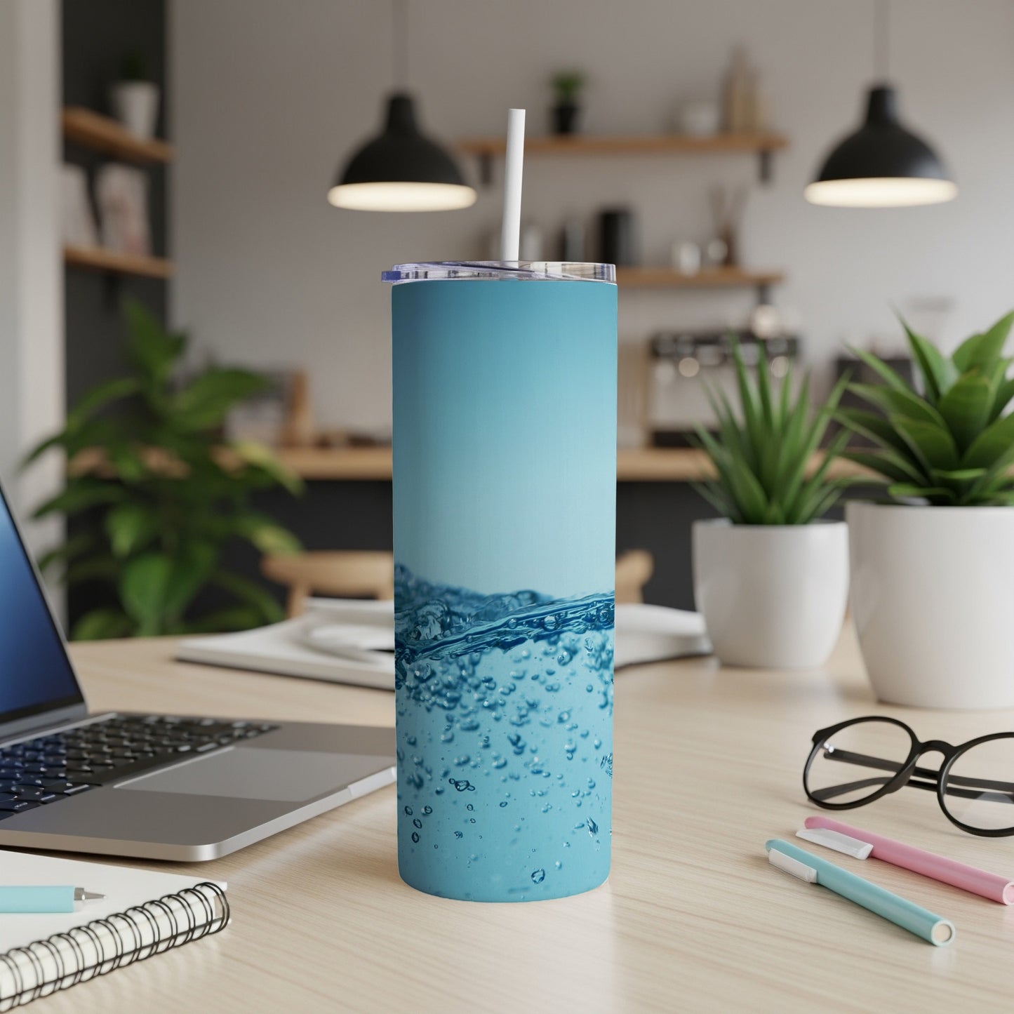 Blue tumbler with bubbly water texture and white straw on a desk.