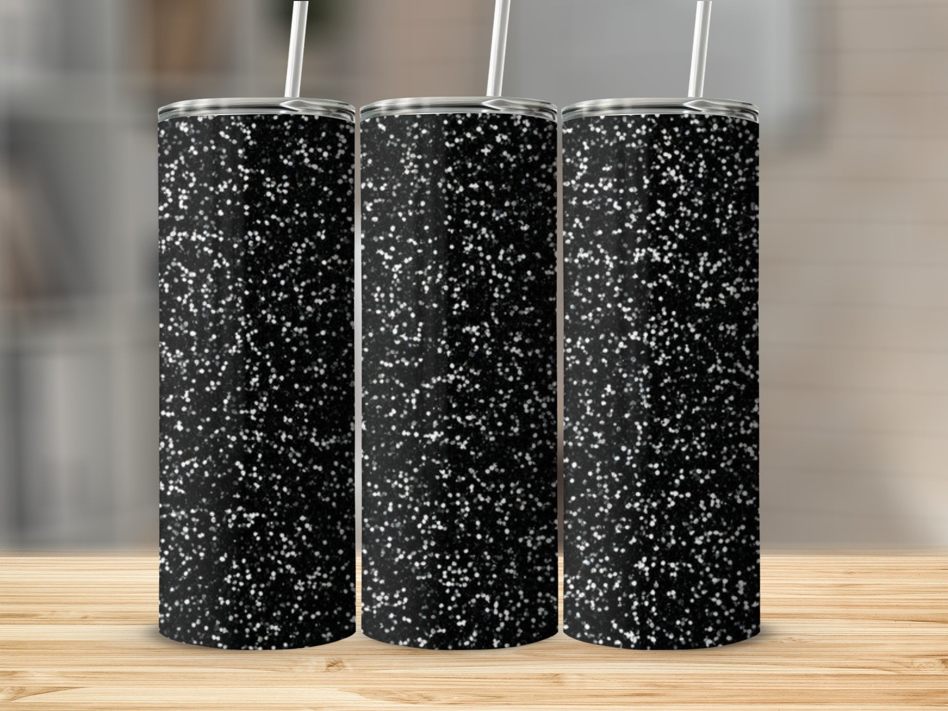 Three black tumblers with a white glitter pattern sit on a wooden surface.