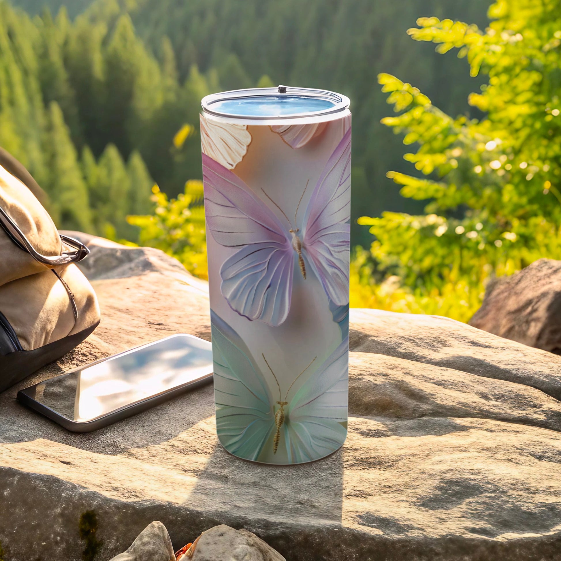 Tall tumbler with pastel butterfly pattern resting on rock outdoors.