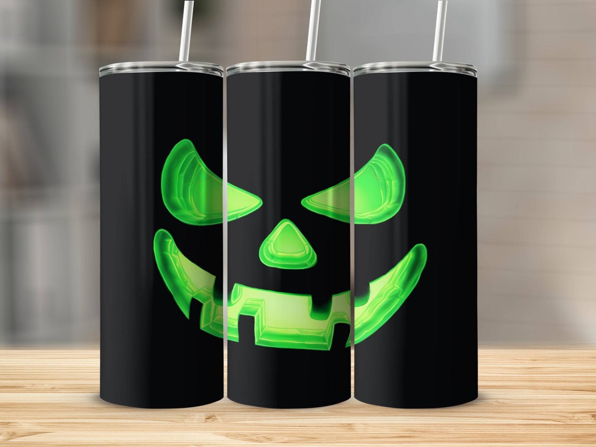 Three black tumblers with glowing green jack-o'-lantern faces and straws.