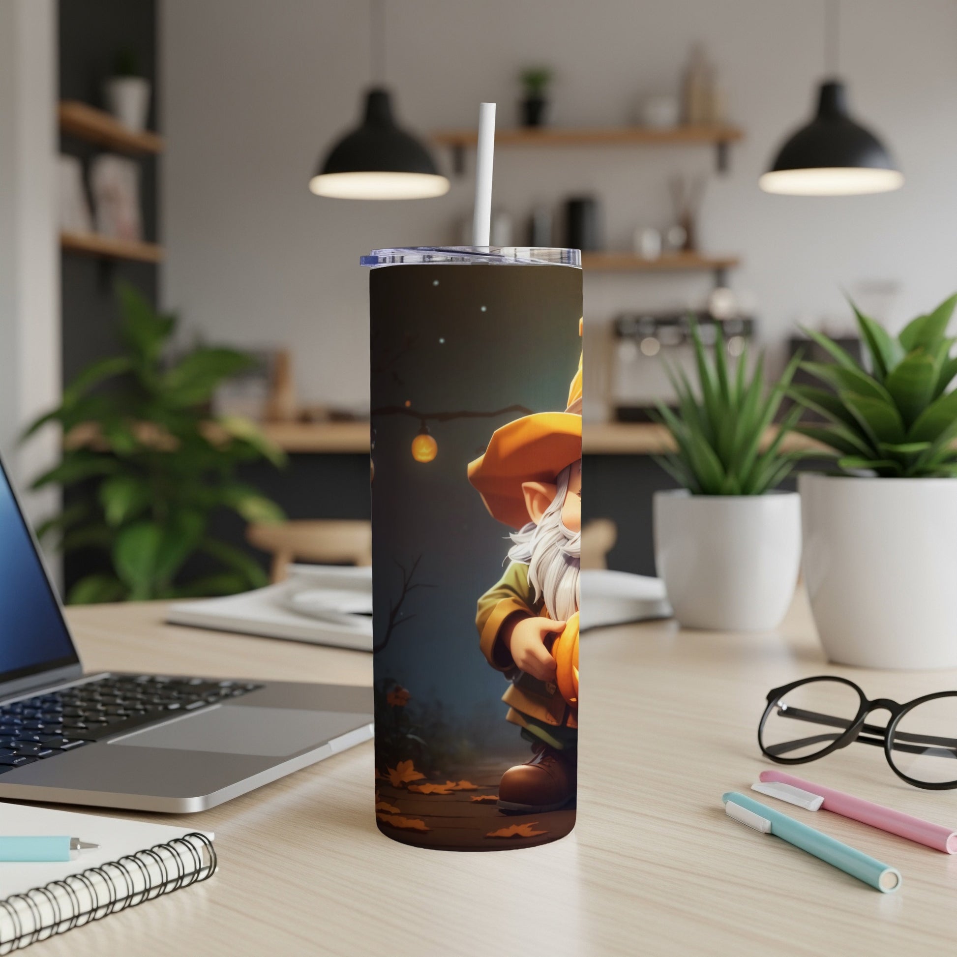 Tumbler with gnome holding pumpkin, on desk with laptop and plants
