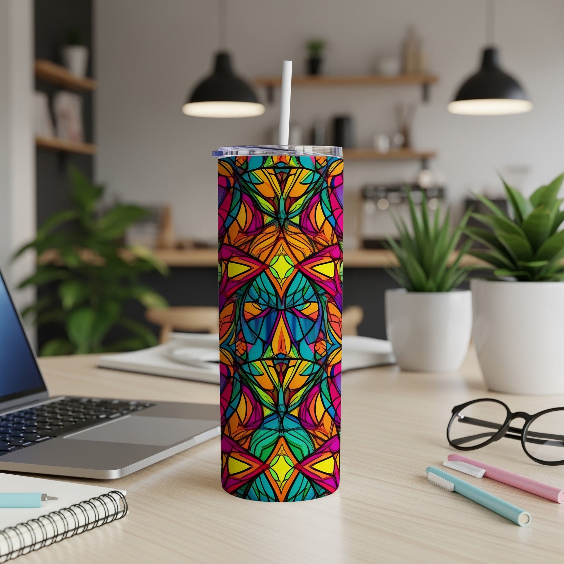 Colorful stained-glass pattern tumbler with straw on a desk.
