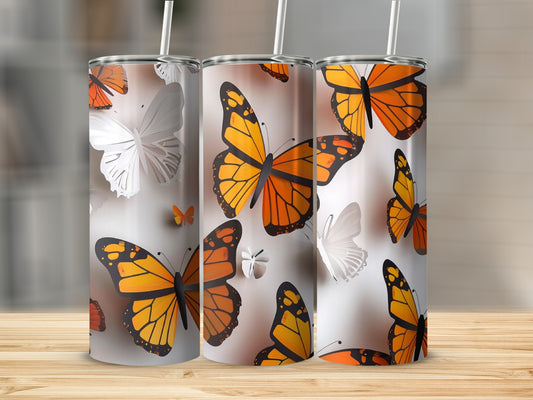 Three tumblers with monarch butterflies on a wooden surface.