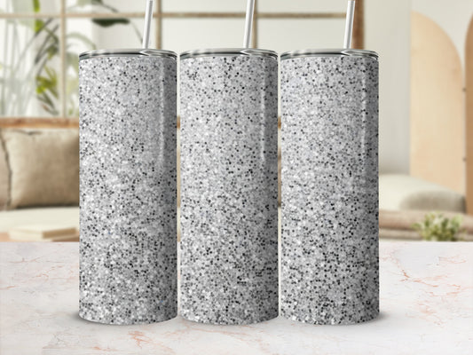 Three silver glitter tumblers with straws on a marble surface.