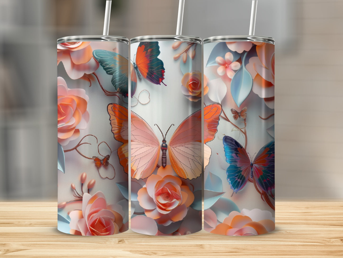Three tumblers with floral and butterfly designs stand on a wooden surface.