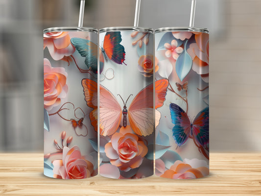 Three tumblers with floral and butterfly designs stand on a wooden surface.
