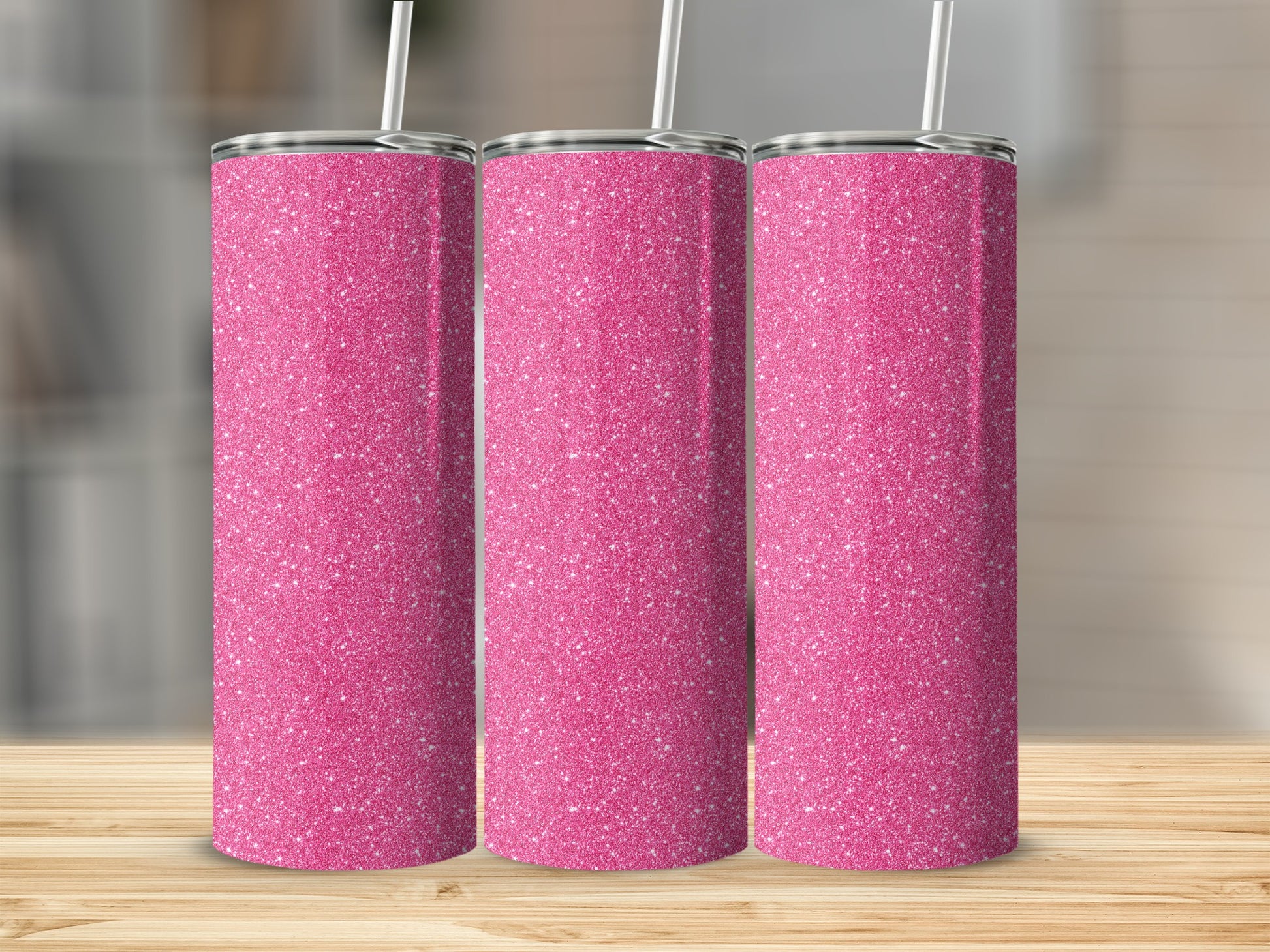 Three pink glitter tumblers with straws stand on a wooden surface.