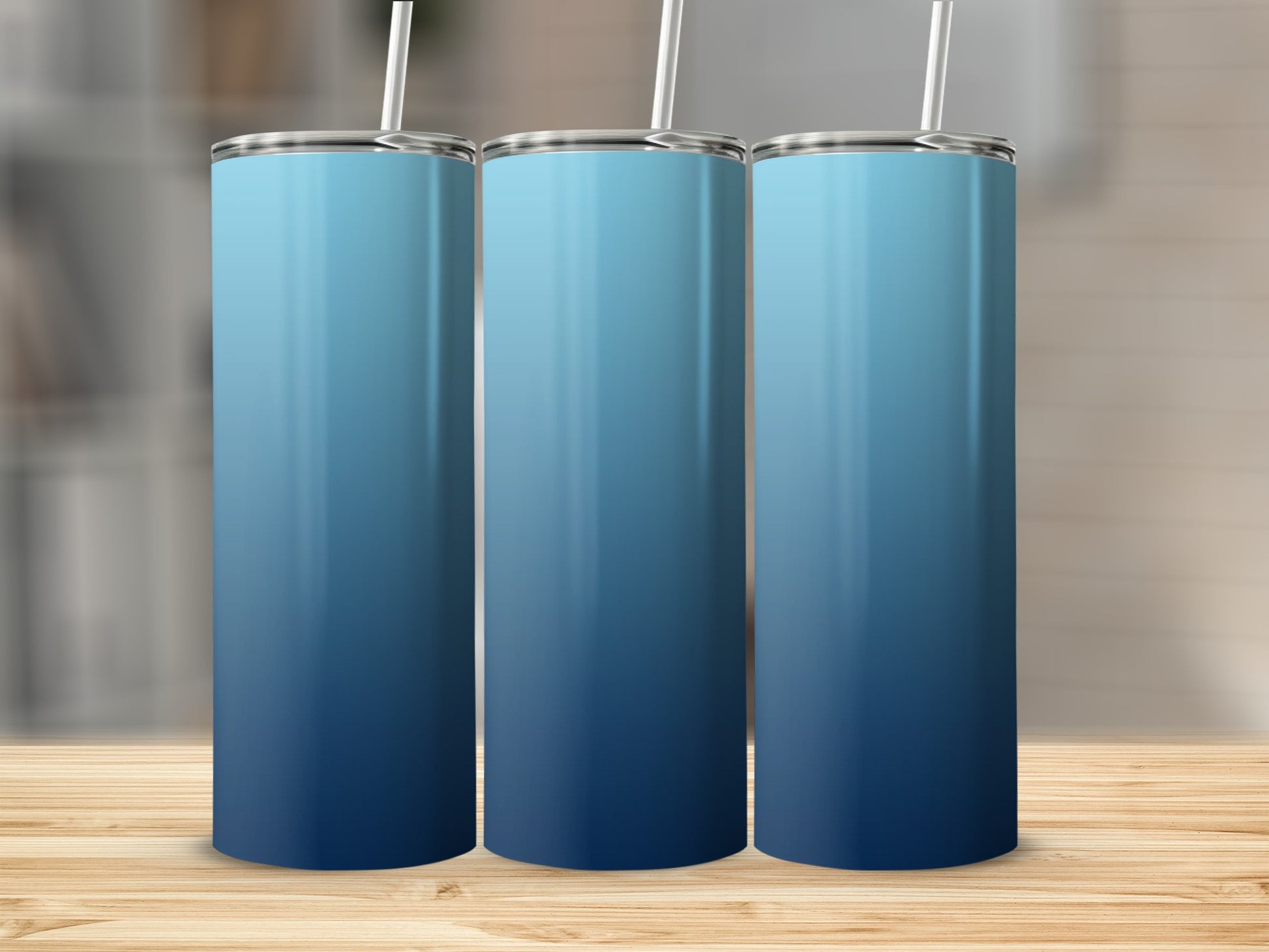 Three blue gradient tumblers with white straws on a wooden surface.