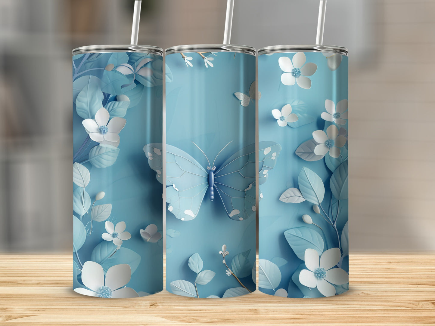 Blue butterfly and floral pattern on three light blue tumblers.