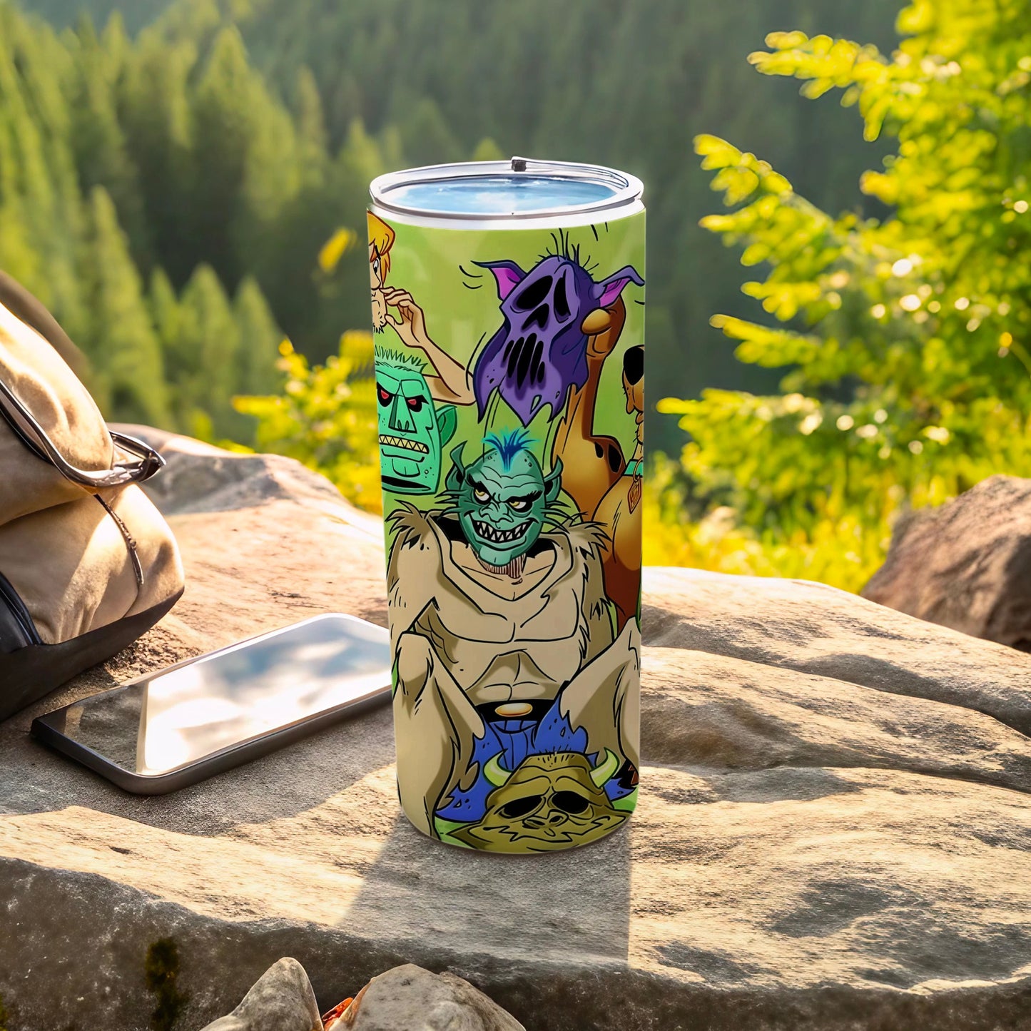 Colorful cartoon monsters on a tumbler with a nature background and phone.