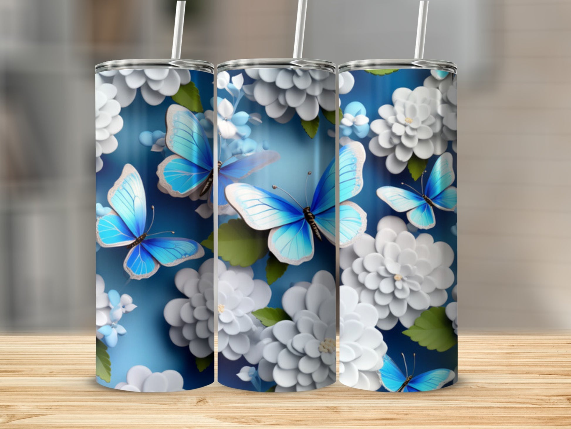 Three tumblers with blue butterflies and white flowers on a blue background.